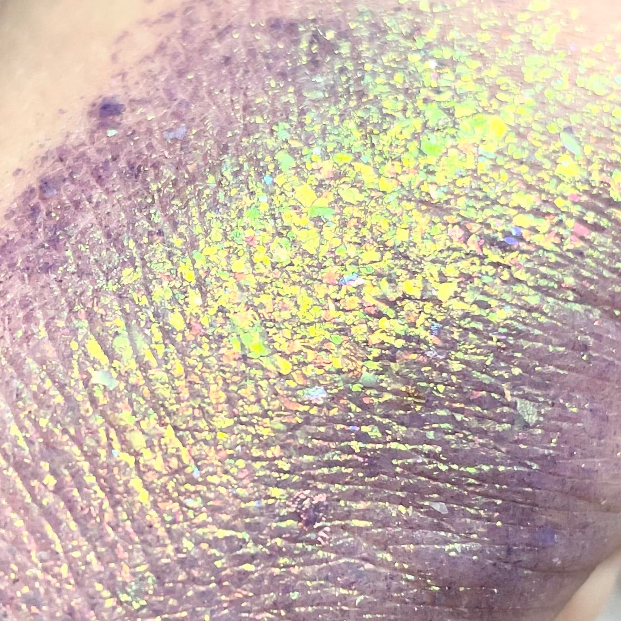 Purple and yellow glitter eyeshadow with iridescent shimmer on skin