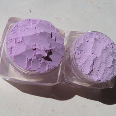 Hand applying shimmery purple loose mineral eyeshadow with a brush, showcasing pigmented blendable texture