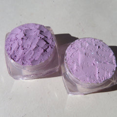 Close-up of three vibrant purple loose mineral eyeshadows with shimmering mica flecks in glass jars