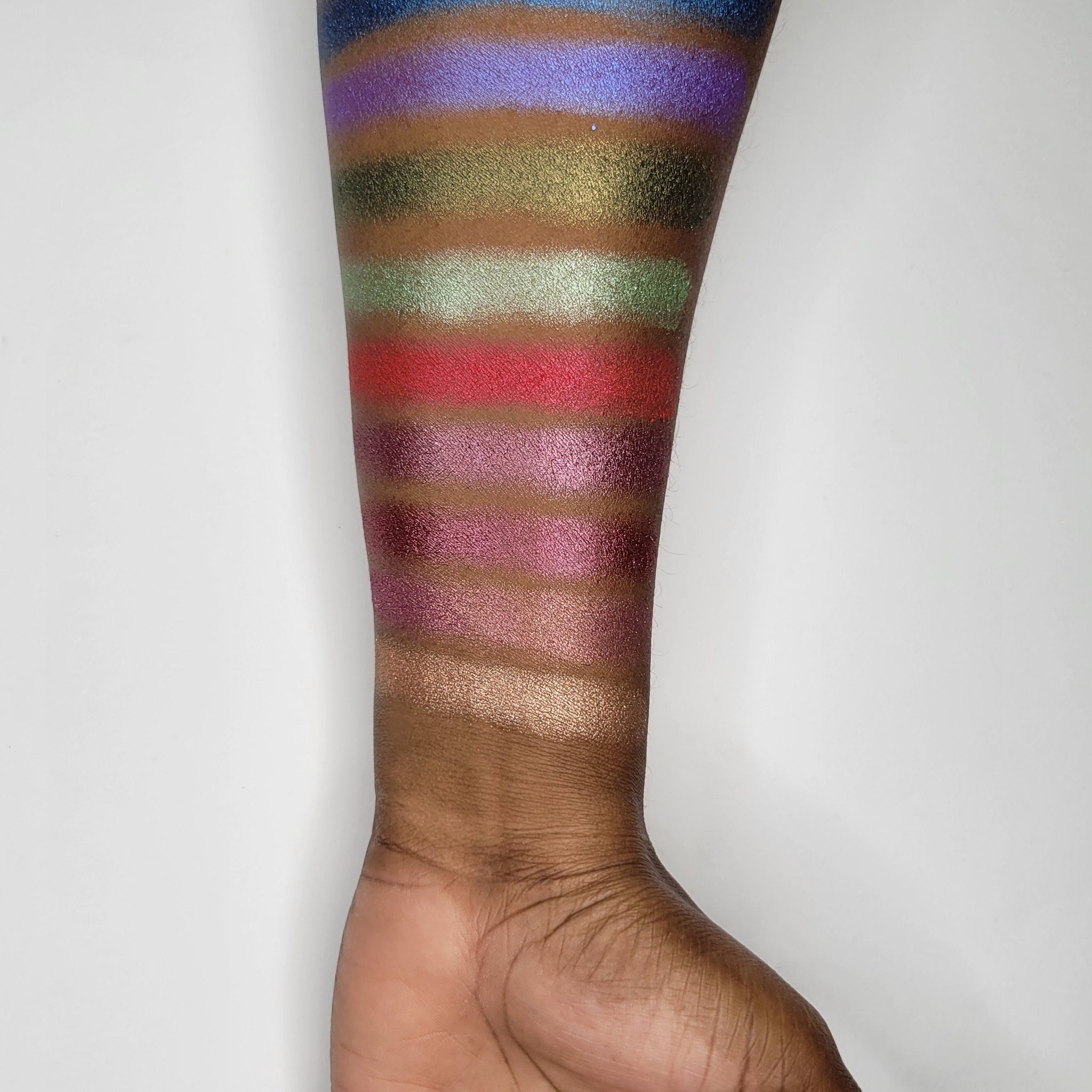 Close-up swatch of Gracidea hot pink eyeshadow with vibrant red undertones on fingertip