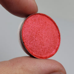 Close-up of vibrant hot pink and red eyeshadow pan with smooth, highly pigmented texture