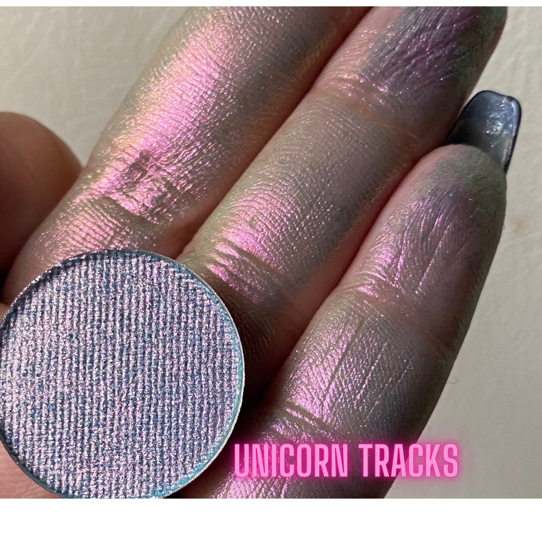 Swatch of multichrome eyeshadows shifting colors under light on fingertips