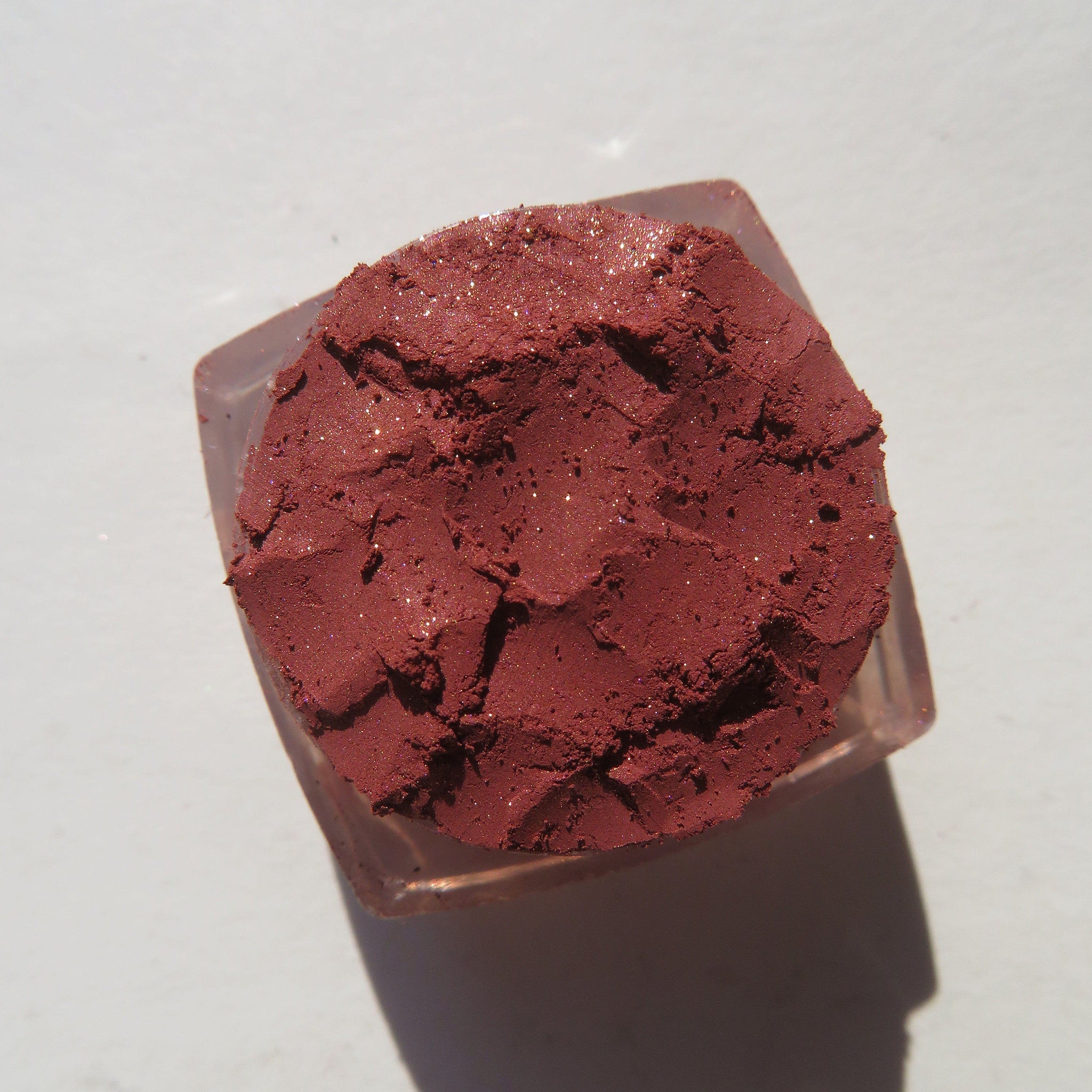 Side view of brick red-orange shimmer loose mineral eyeshadow with metallic finish in eco-friendly packaging