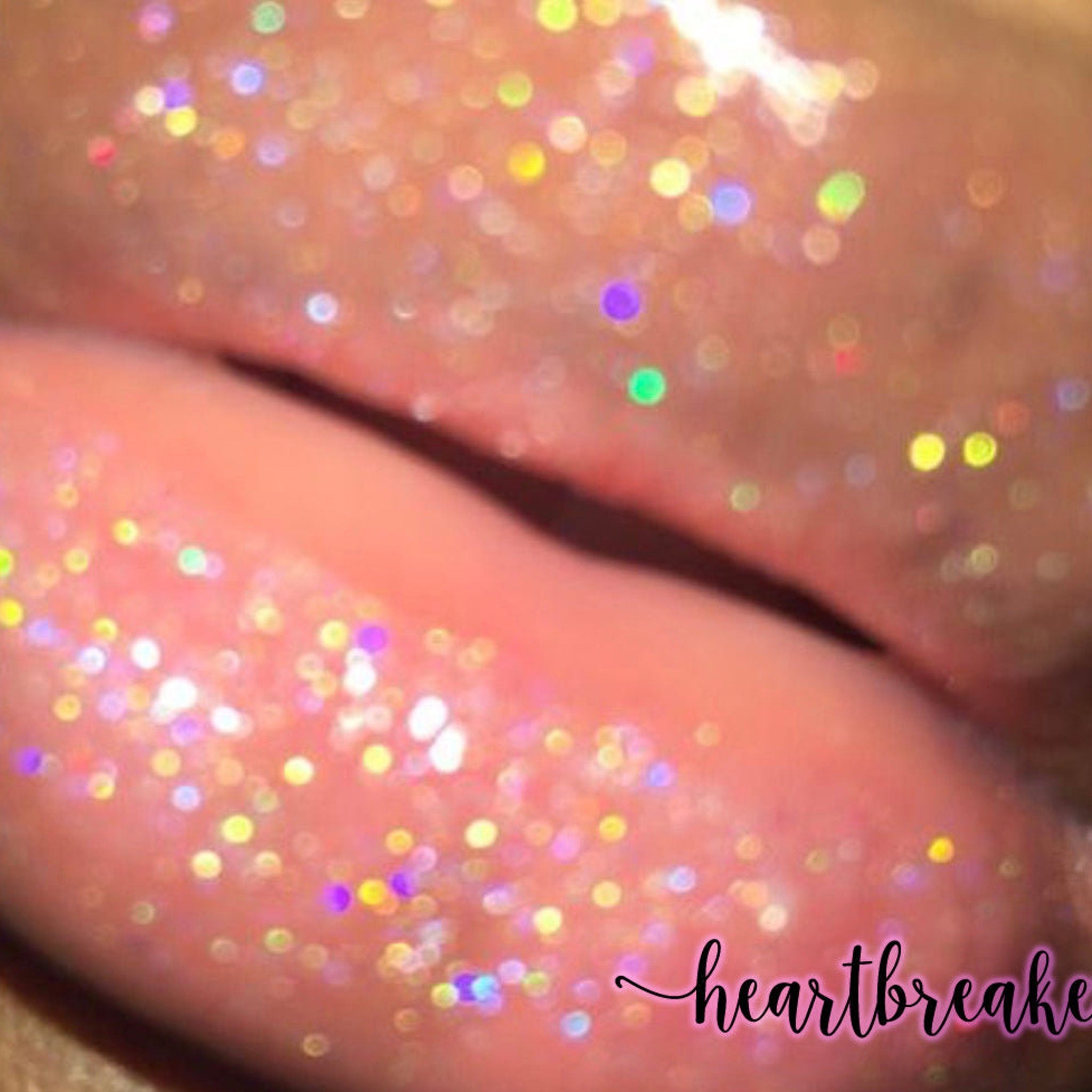 Lip gloss with peach color, glitter, and "heartbreak" text
