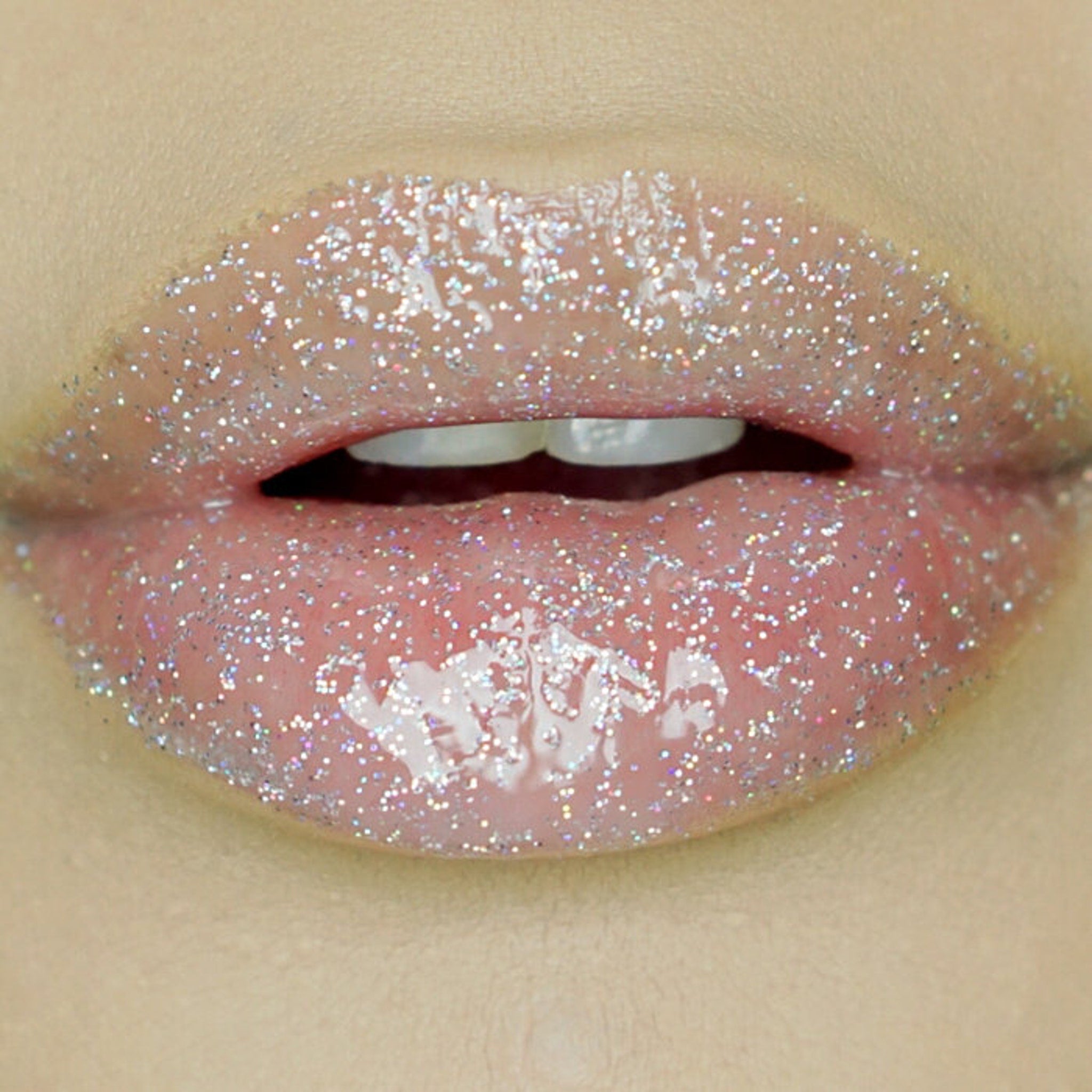 Lip gloss with silver glitter, pink color, and glossy finish on lips