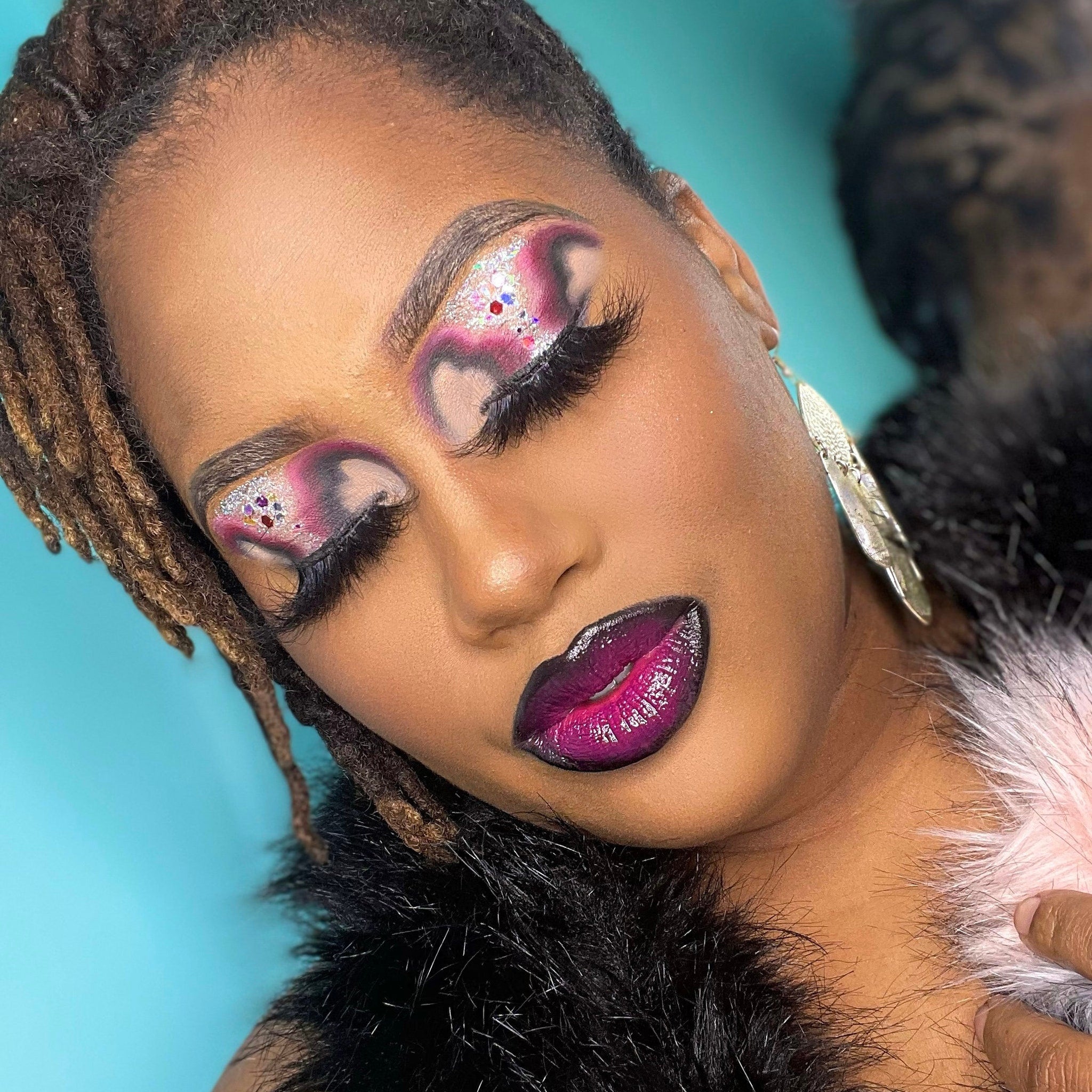 Makeup look with pink and silver eyeshadow, dark purple lipstick, and black feather boa