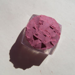 Hand applying pale pink shimmer loose mineral eyeshadow with a fluffy brush for a soft glow