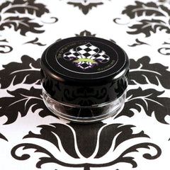 Dark purple loose mineral eyeshadow spilled on marble surface with brush for application