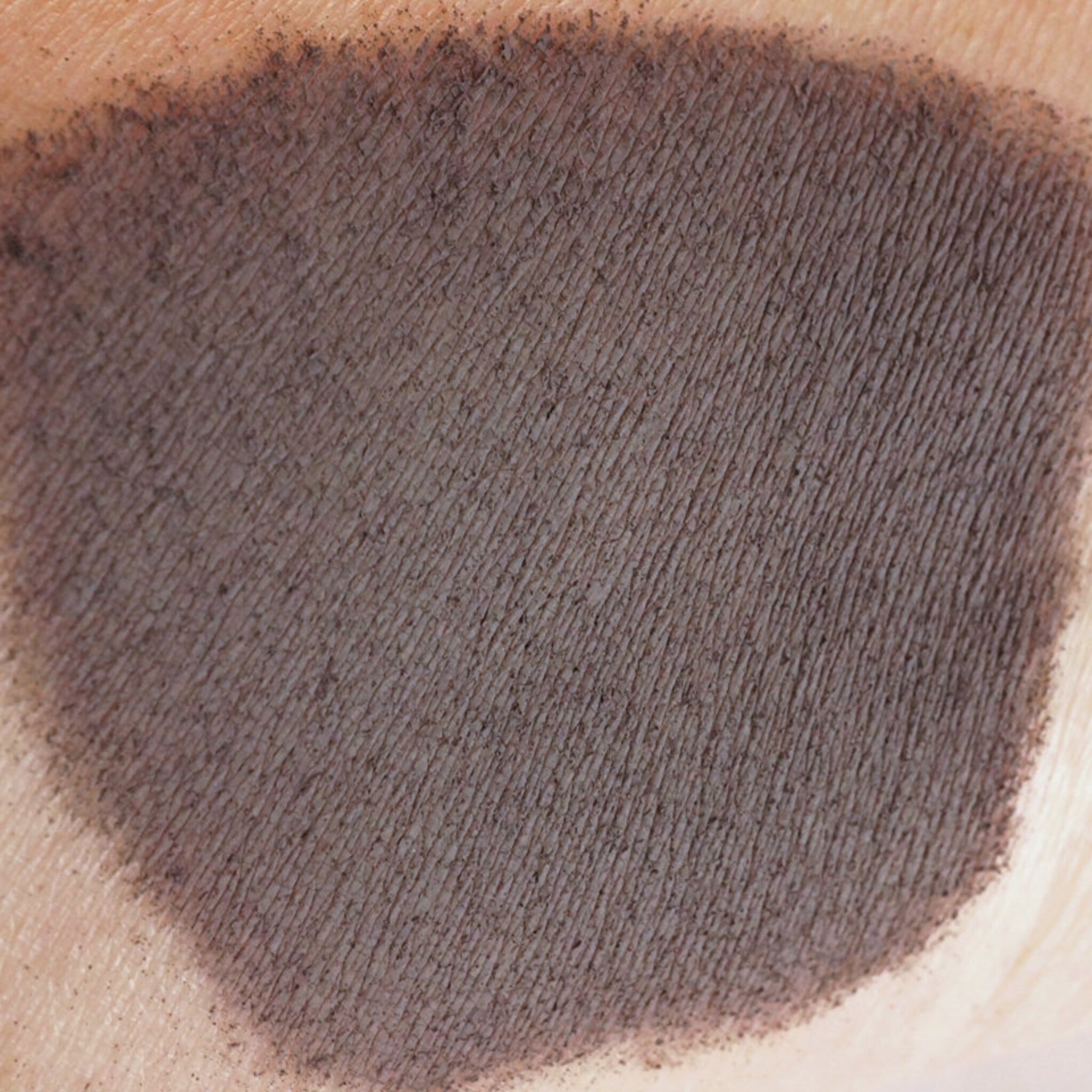 Close-up of matte dusty violet loose pigment eyeshadow in dark purple-gray shade, showing fine powder texture