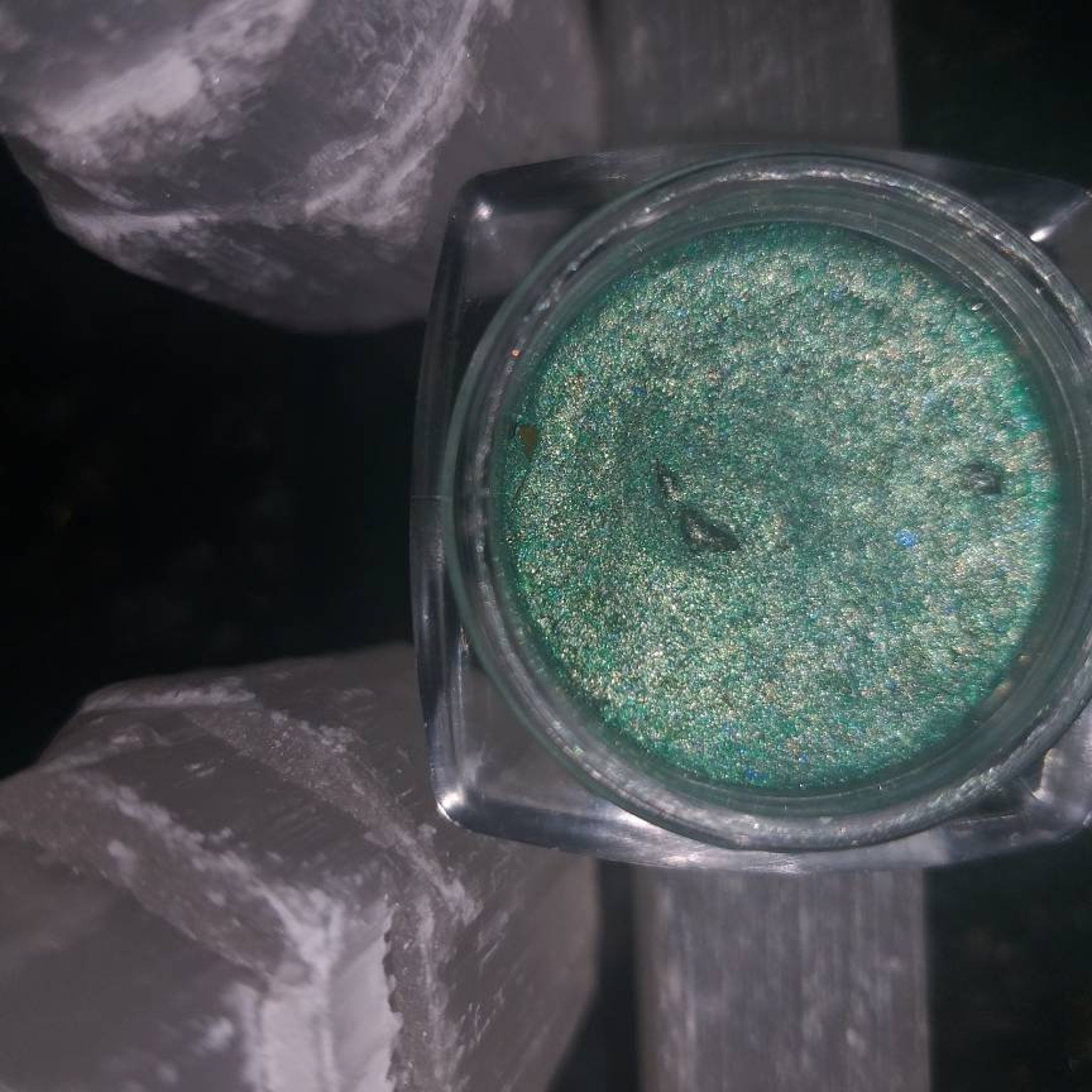 Side view of peacock-inspired eyeshadow palette showing vibrant blue and green shimmery shades in compact case