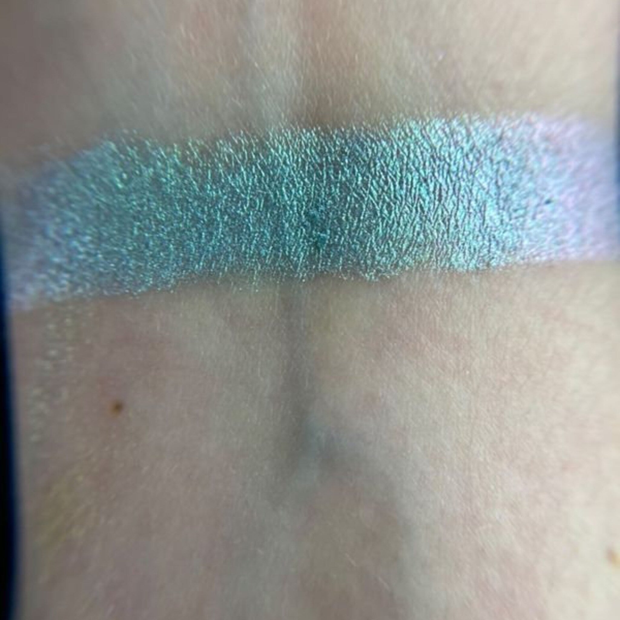 Close-up of fingertips applying shimmery teal eyeshadow from Fairy Frog palette onto eyelid
