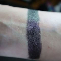 Close-up of fingertips applying shimmery taupe eye shadow to eyelid with soft blending brush
