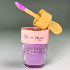 Lip gloss bottle with purple liquid, pink lid, and yellow applicator, "Spun Sugar" text visible