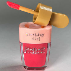 Lip gloss with pink and gold applicator, "Birthday Girl" text, and "POP & POLISHED" label visible