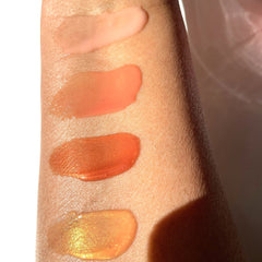 Lip gloss swatches in various shades of pink, orange, and gold on skin, Brownsugarglamcollection