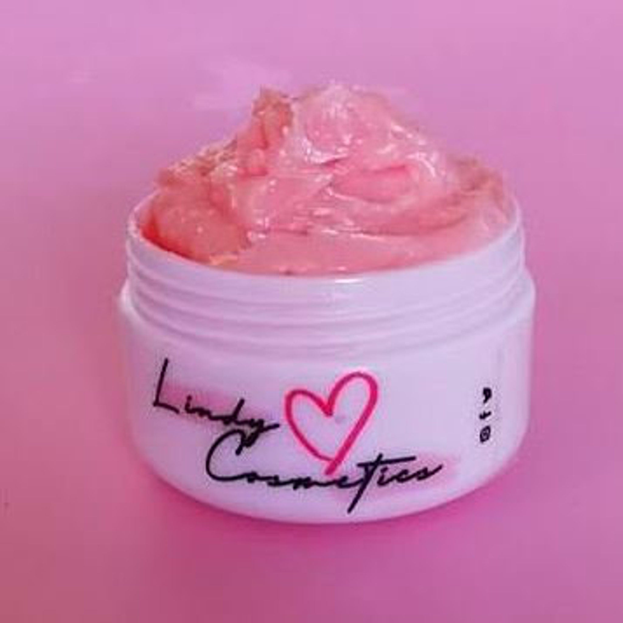 Lip balm in white jar with pink cream and Lindy Cosmetics logo on pink background