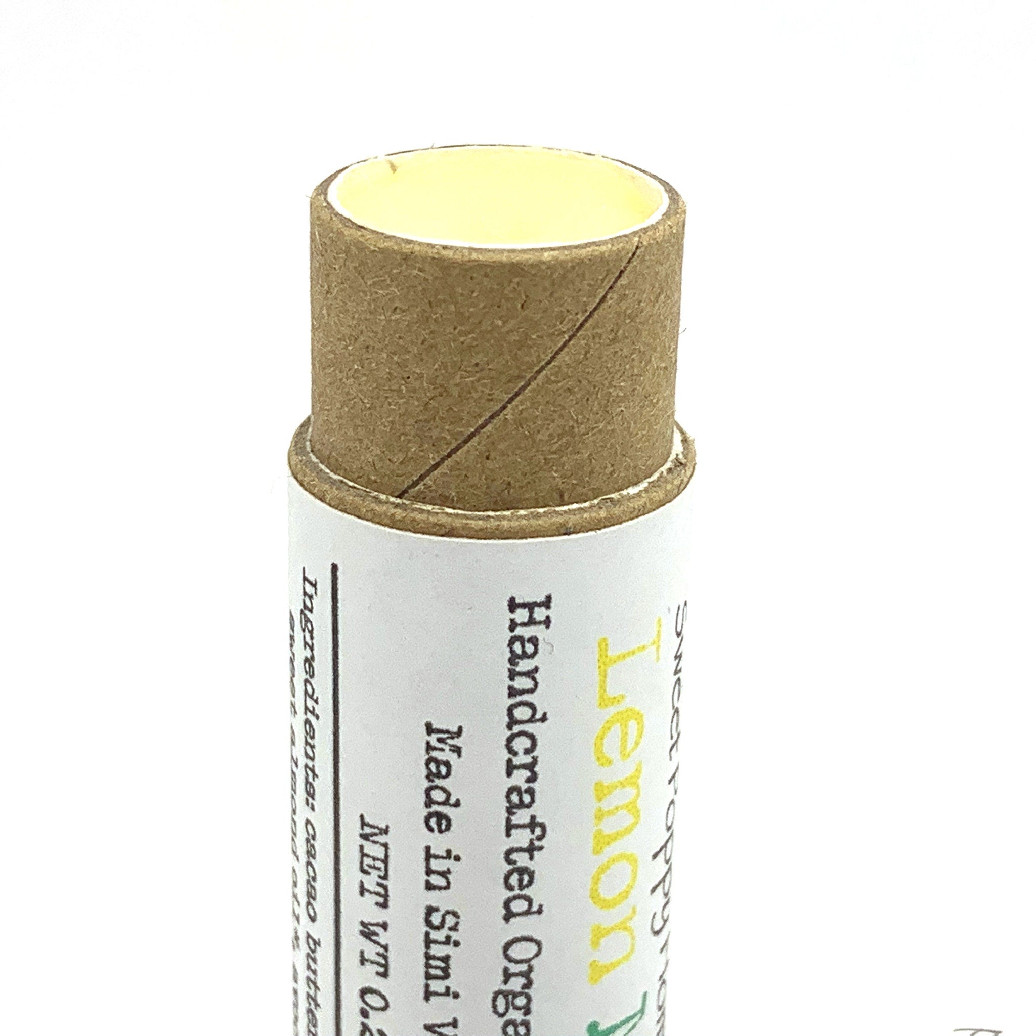 Lip balm tube with yellow balm, brown cardboard, and white label with text