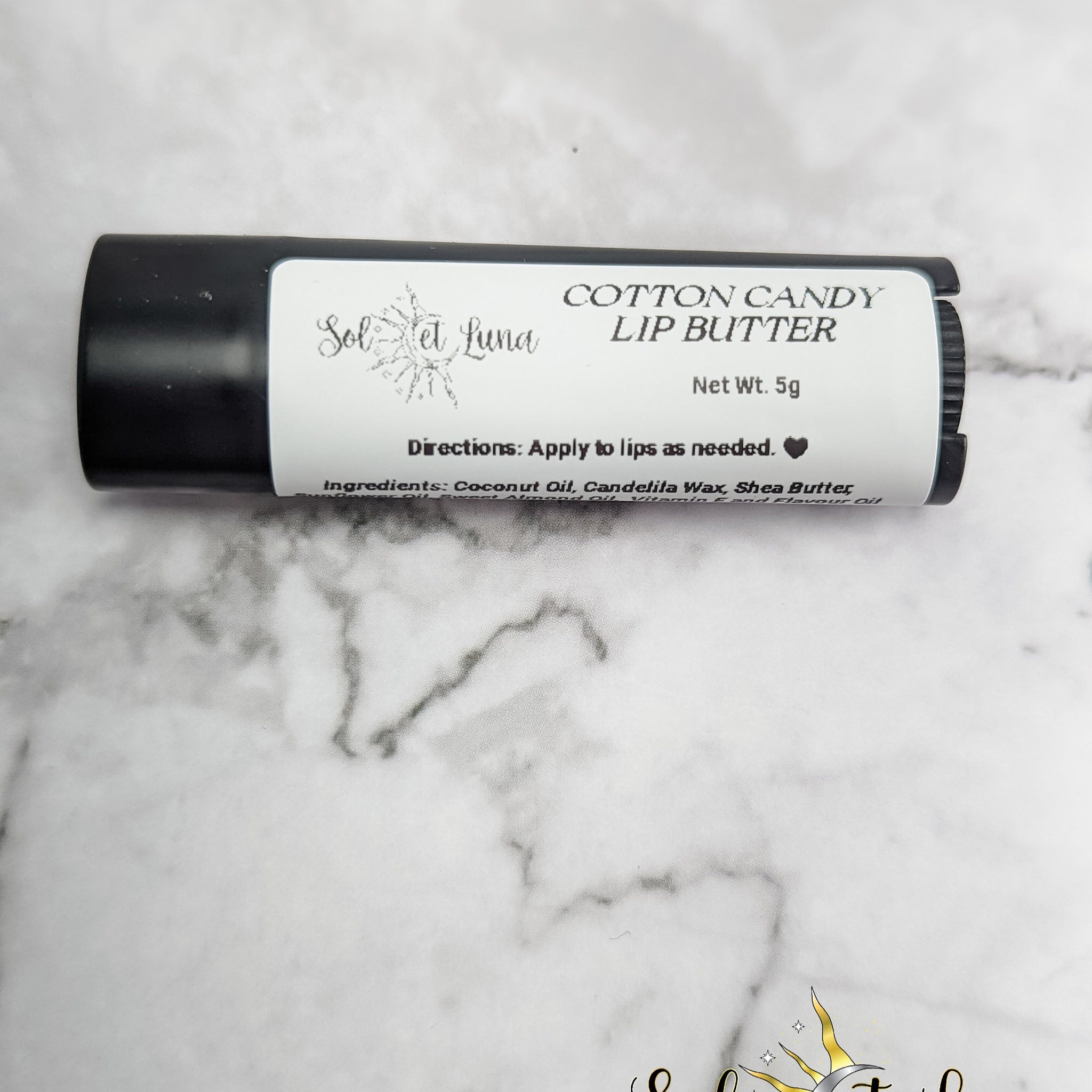 Lip butter stick, black tube, white label with text, Sol et Luna brand name visible