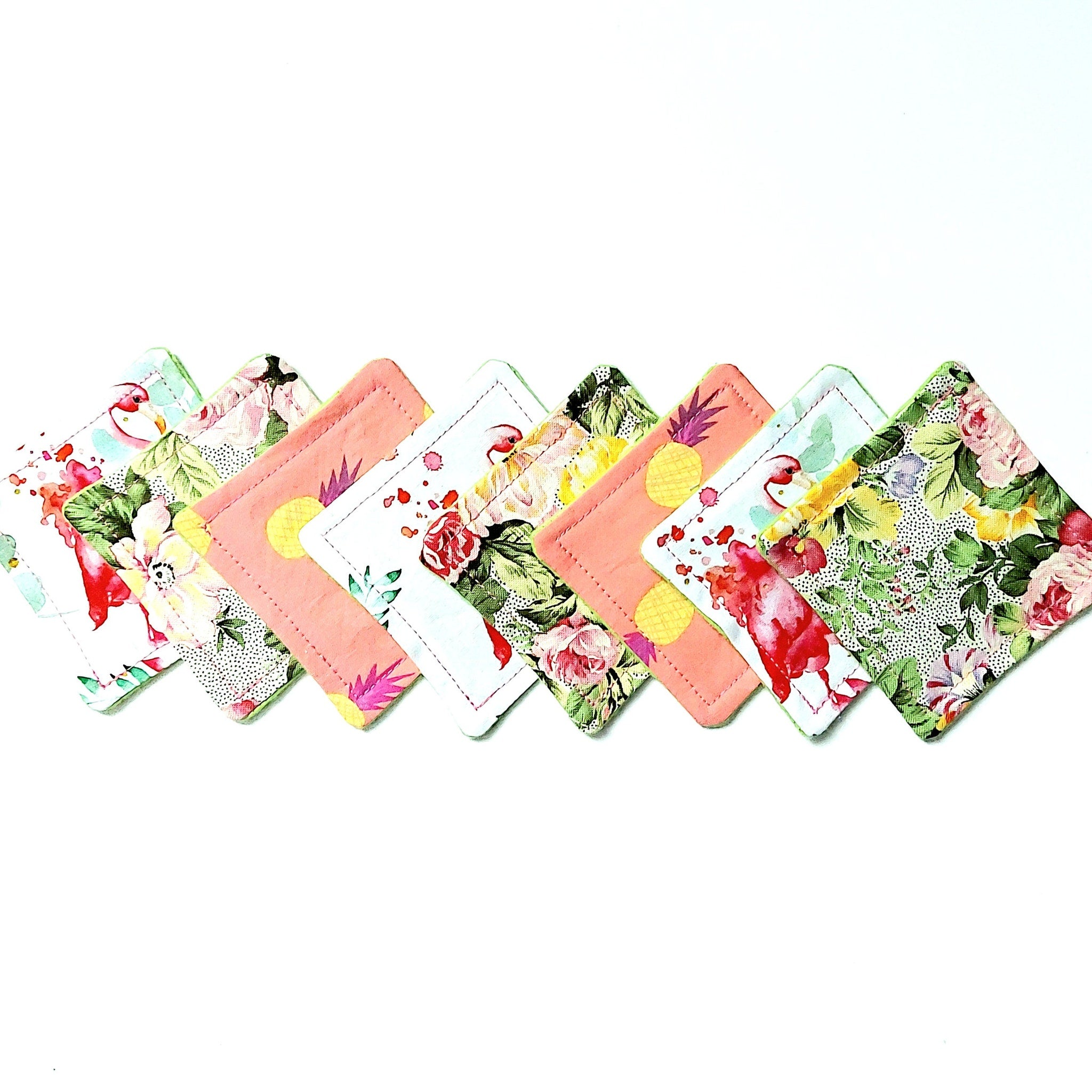 Coasters with floral and solid patterns in pink, green, white, and yellow colors, arranged in a row
