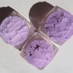 Side view of three purple vegan loose mineral eyeshadows in round pots with sifter lids, showcasing texture and depth