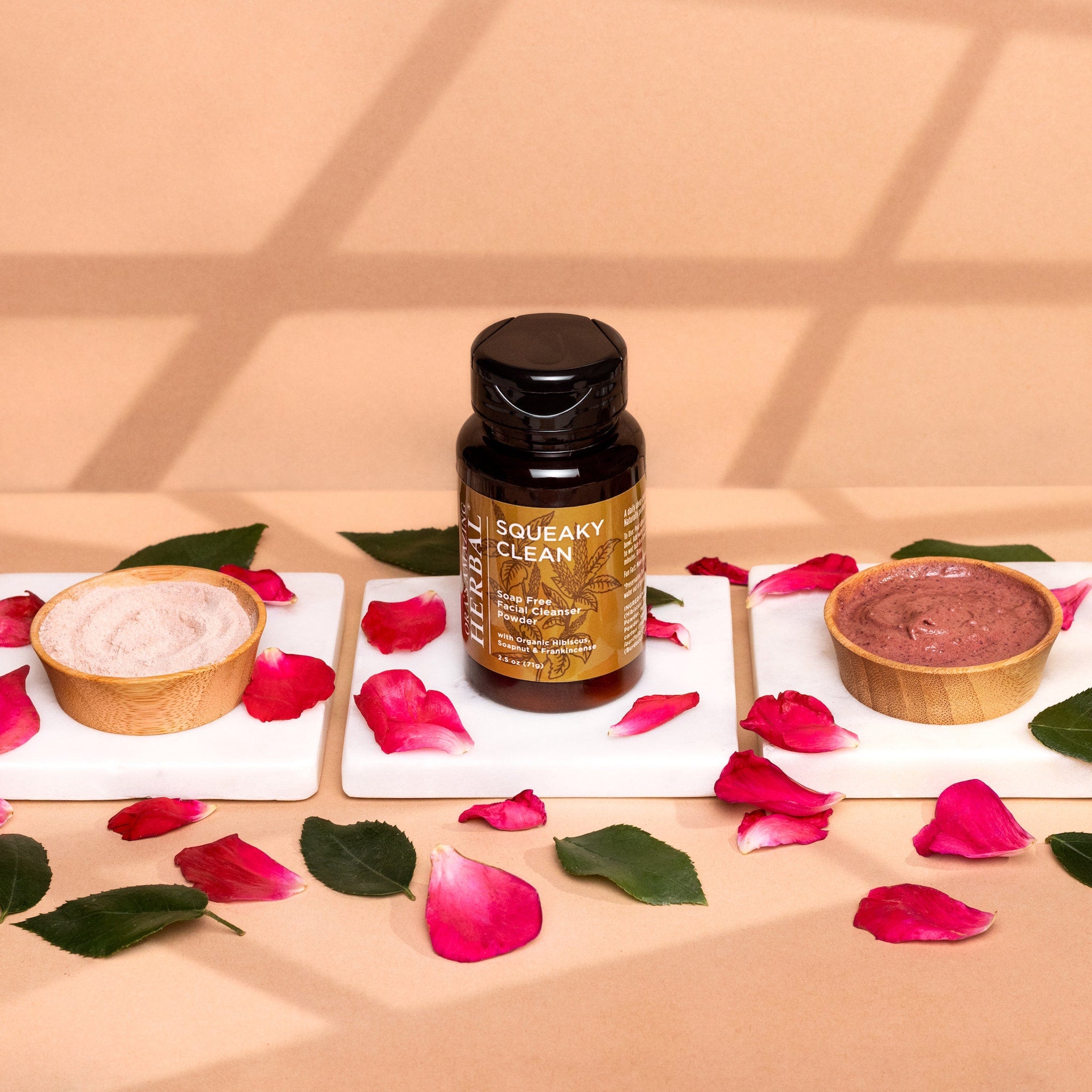 Facial cleanser powder in brown bottle with floral arrangement and SQUEAKY CLEAN label on white surface