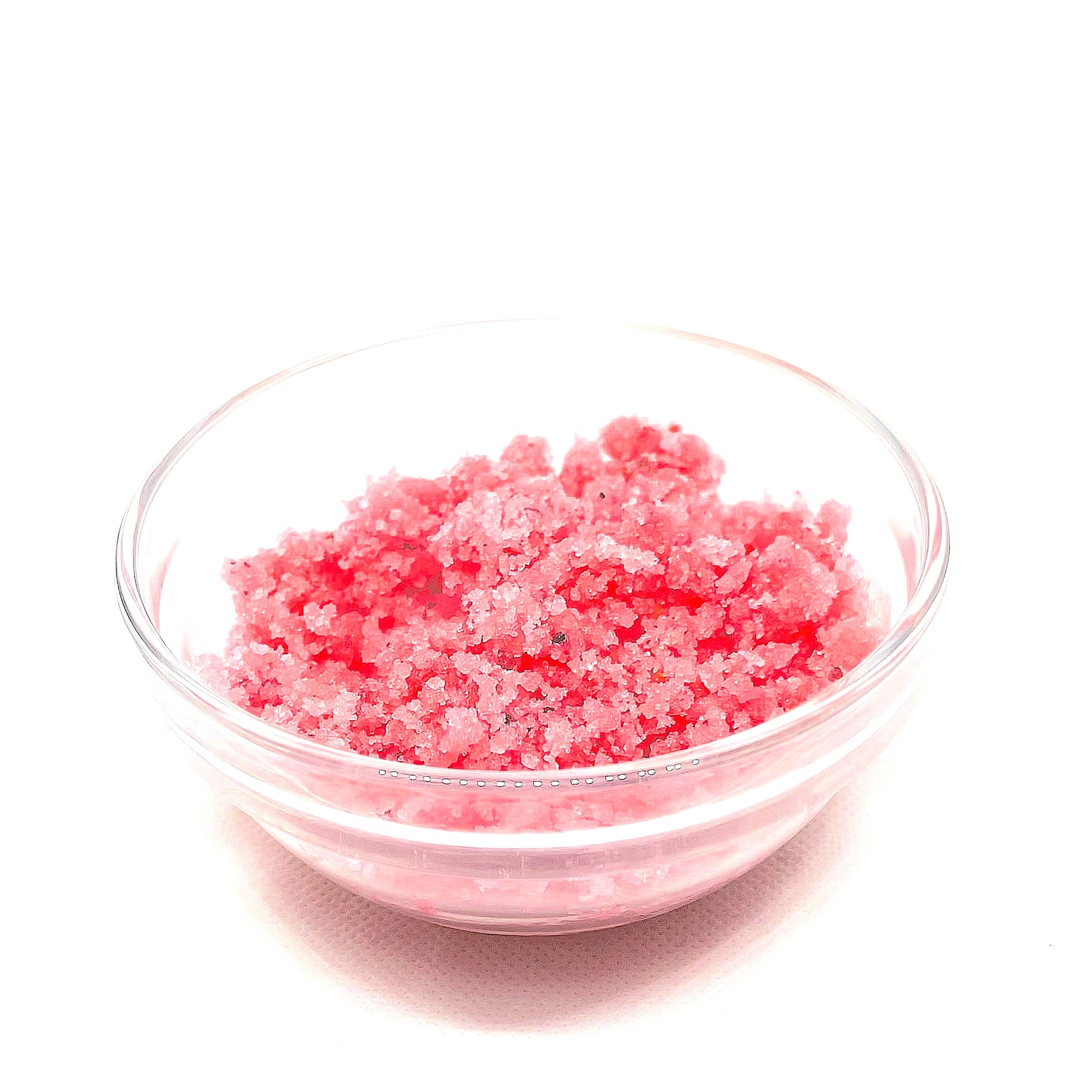 Pink granular substance in a clear glass bowl, isolated on white background