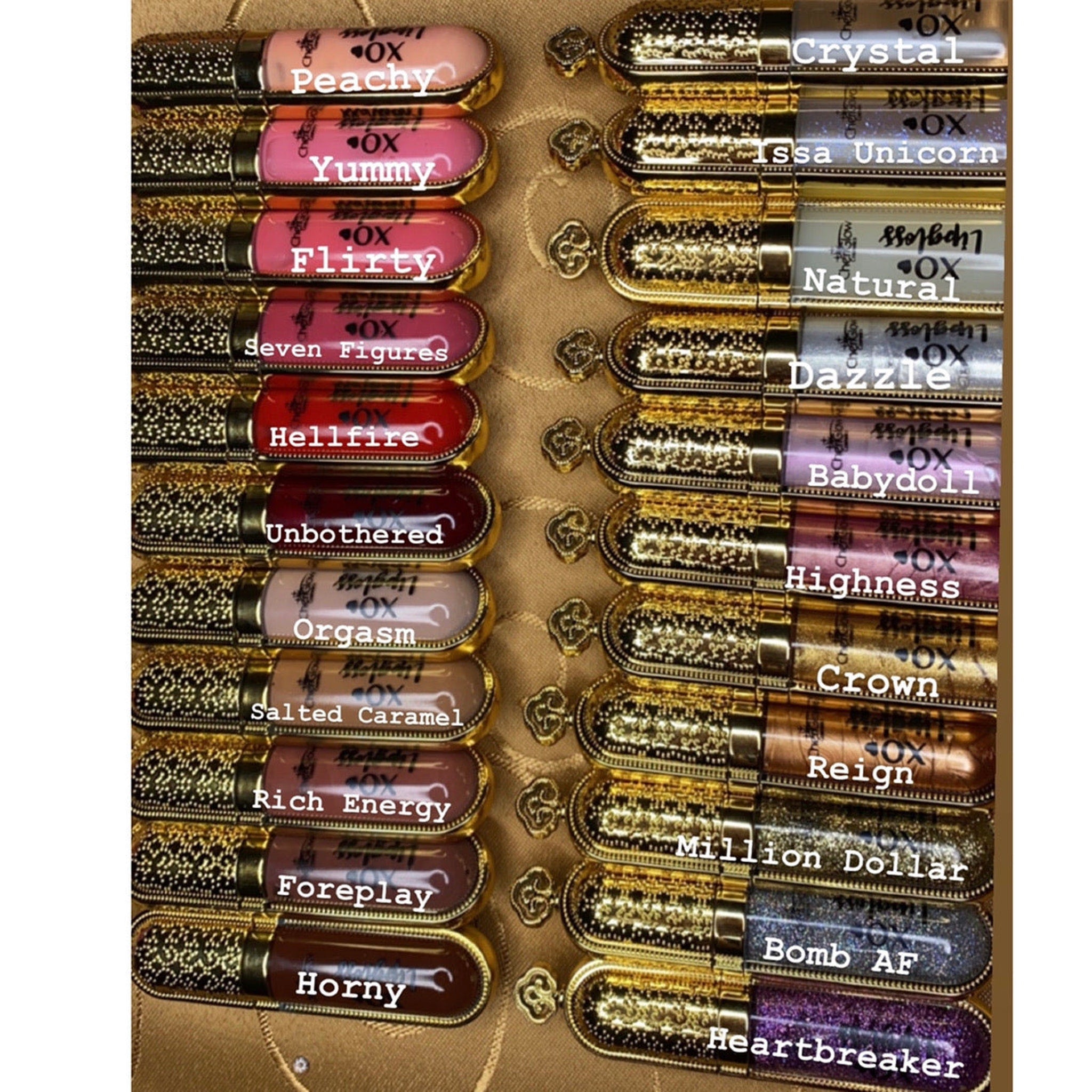 Lip gloss tubes with gold and black patterned caps, various colors, and "OX" brand text.