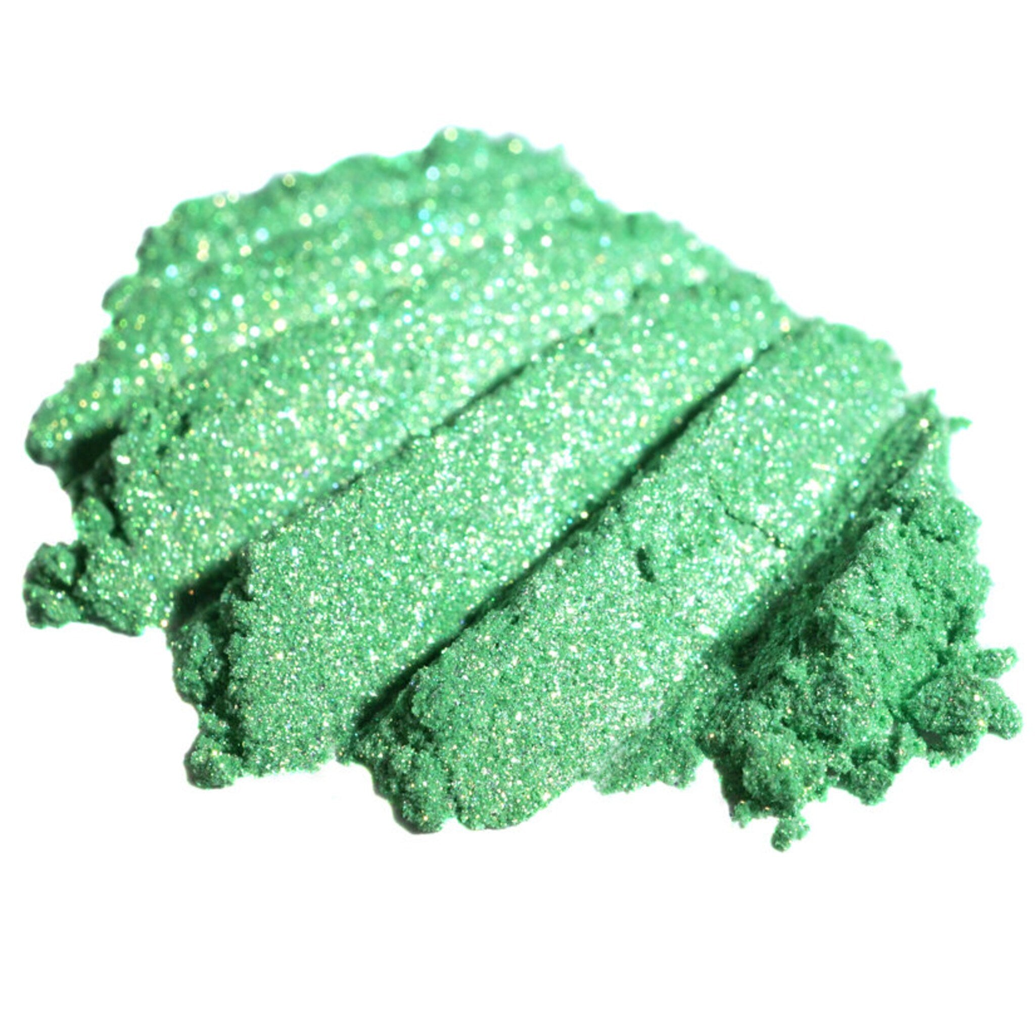 Hand applying iridescent lime green loose eyeshadow pigment with a brush, creating a shimmering metallic effect on eyelid.