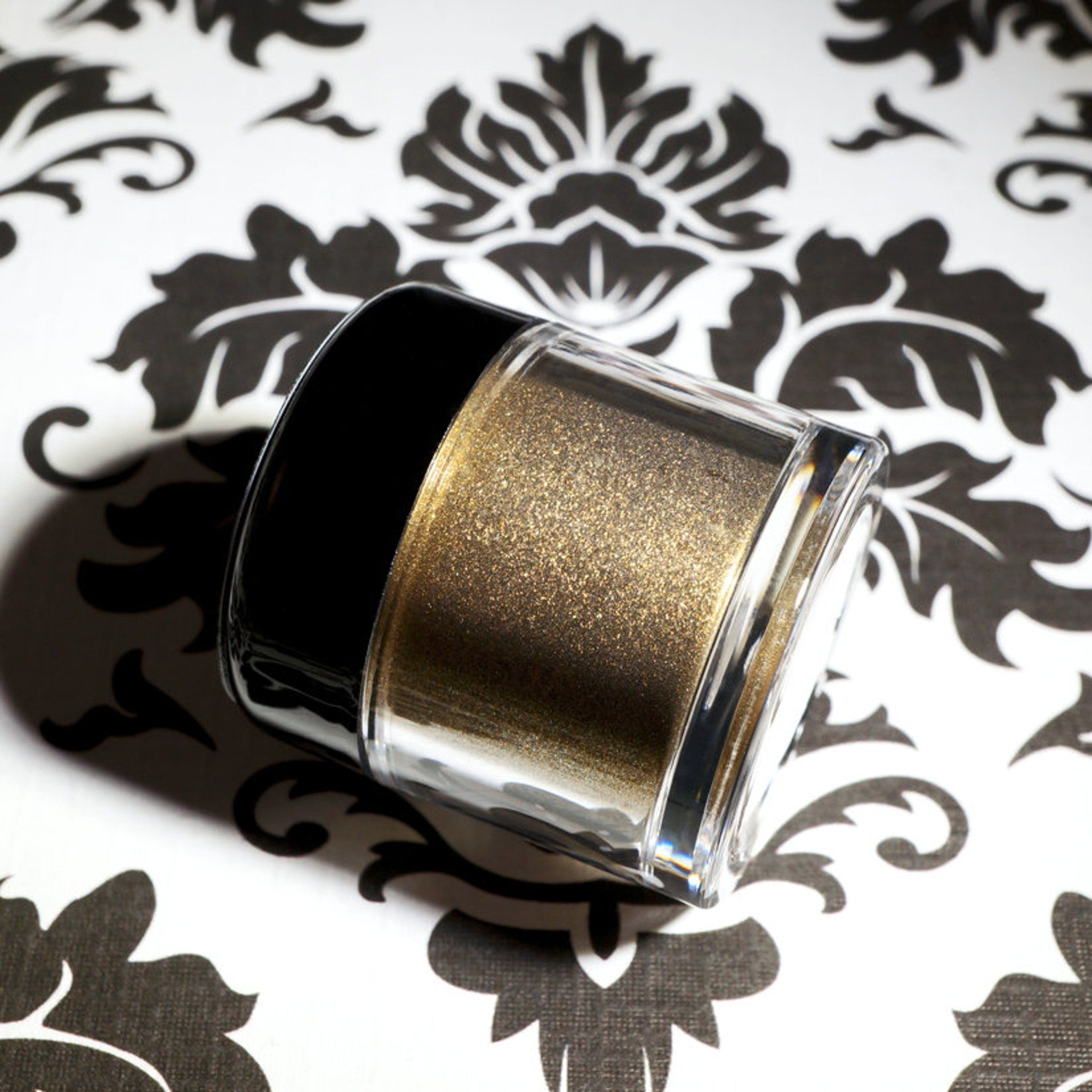 Close-up of loose metallic bronze eyeshadow with dark gold base and vibrant green glitter particles