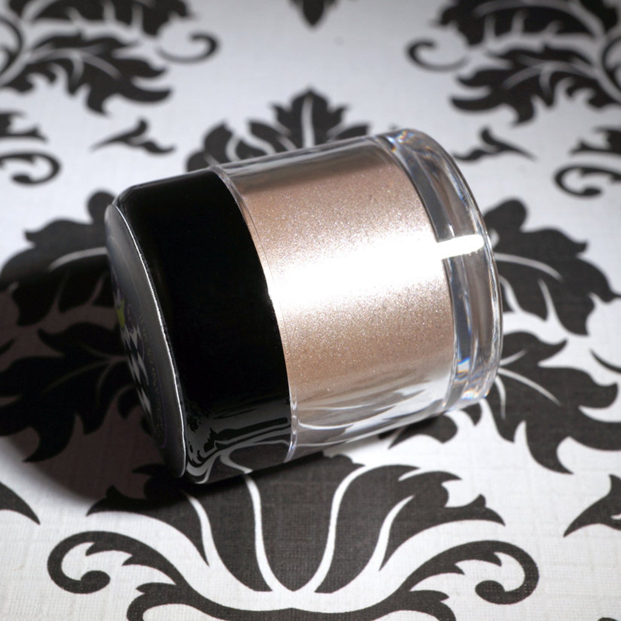 Close-up of loose metallic taupe and champagne eyeshadow pigment with silver shimmer, vegan formula