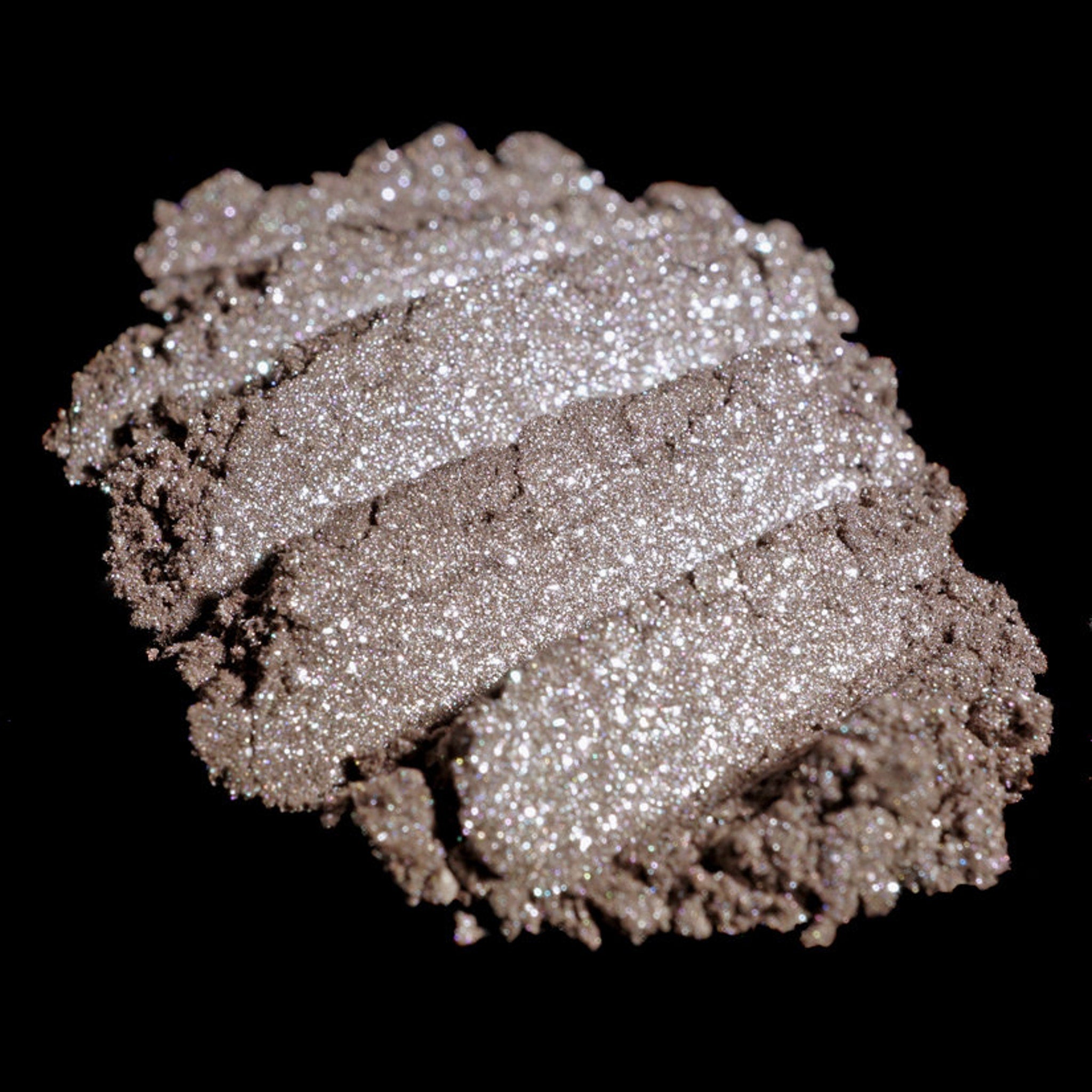 Side view of loose pigment eyeshadow in metallic taupe and champagne with silver shimmer, vegan formula in small jar