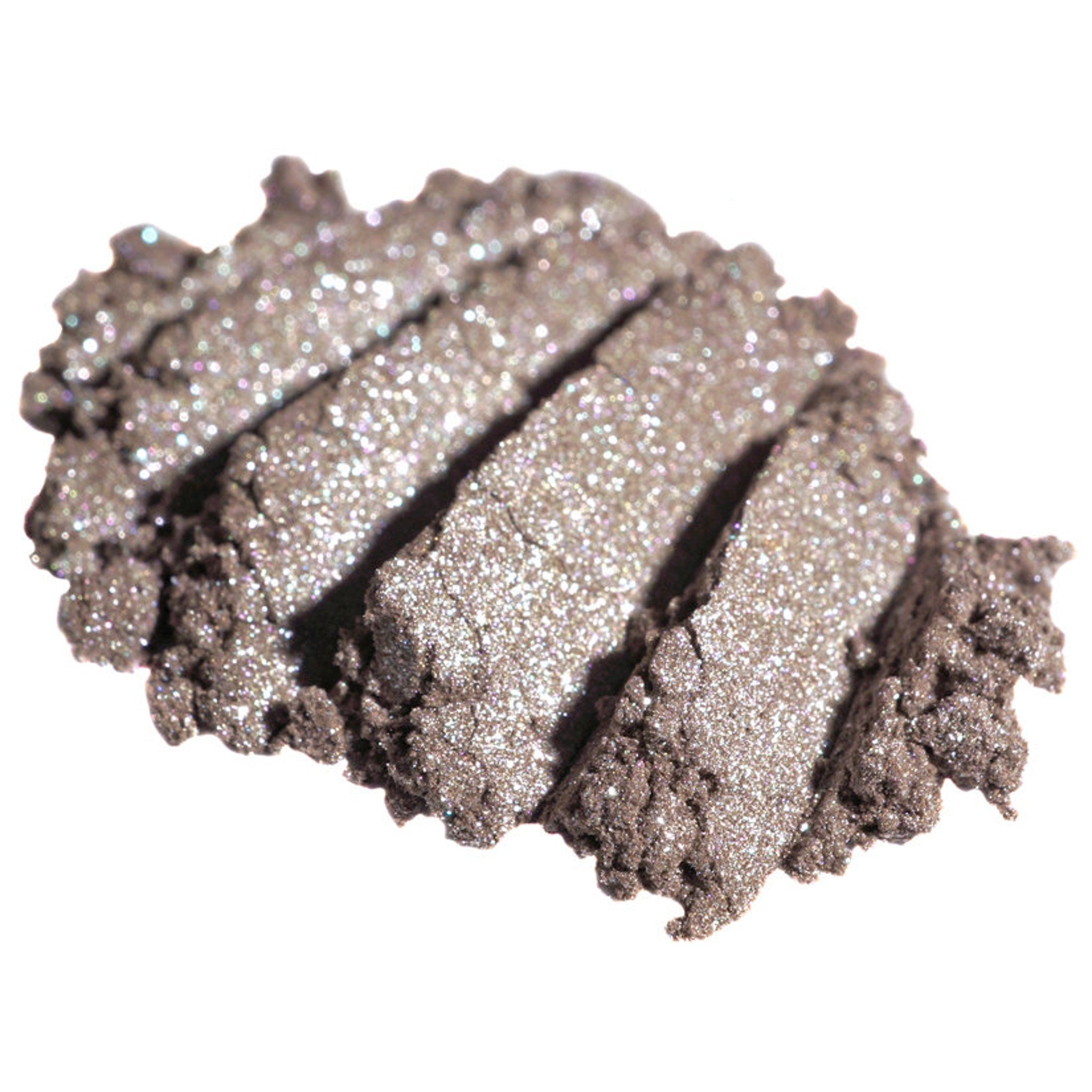 Hand applying metallic taupe loose pigment eyeshadow with silver shimmer to eyelid using fingertip