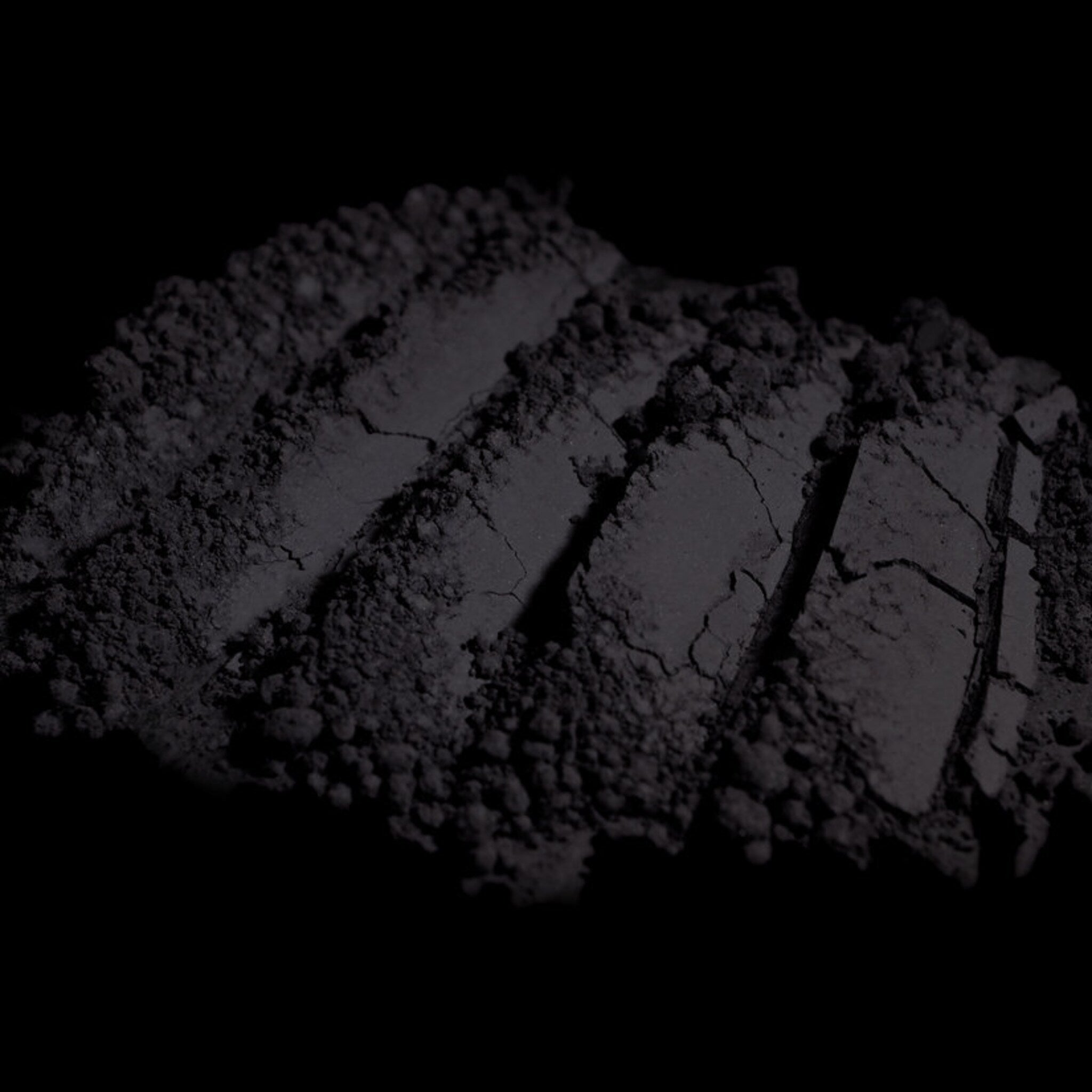 Side view of matte dark purple loose mineral eyeshadow in open jar showing fine powder texture
