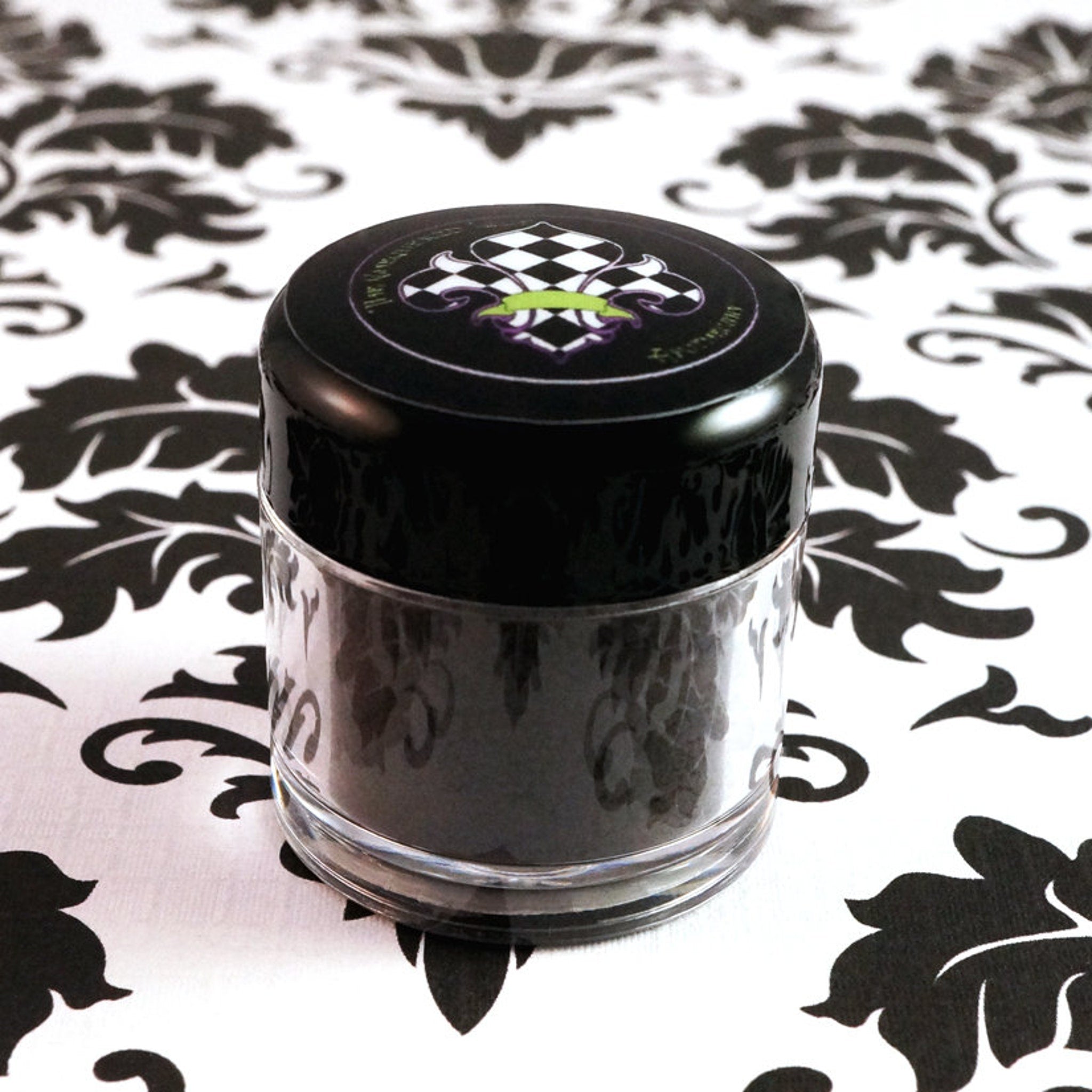 Side view of matte dark purple loose mineral eyeshadow in open jar showing fine powder texture