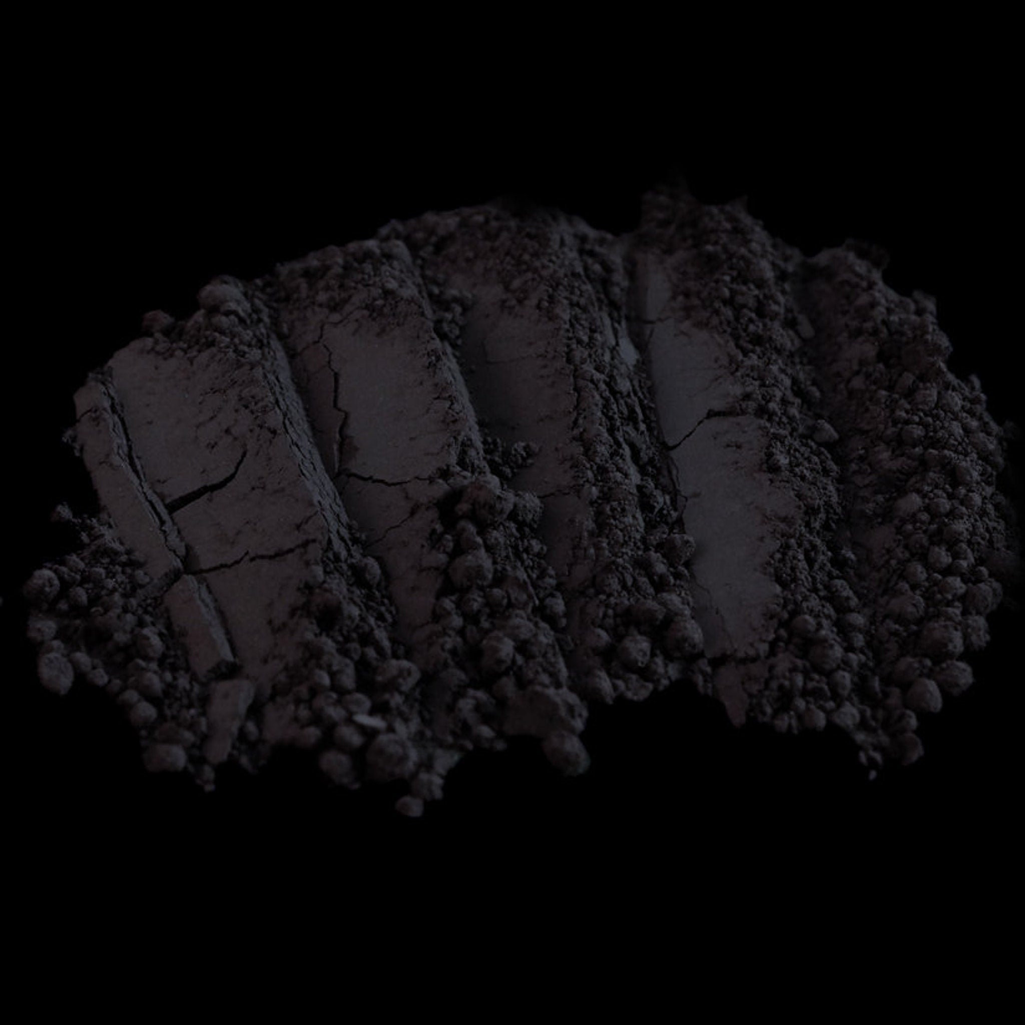 Dark purple loose mineral eyeshadow in a small black jar with silver lid, powder visible inside