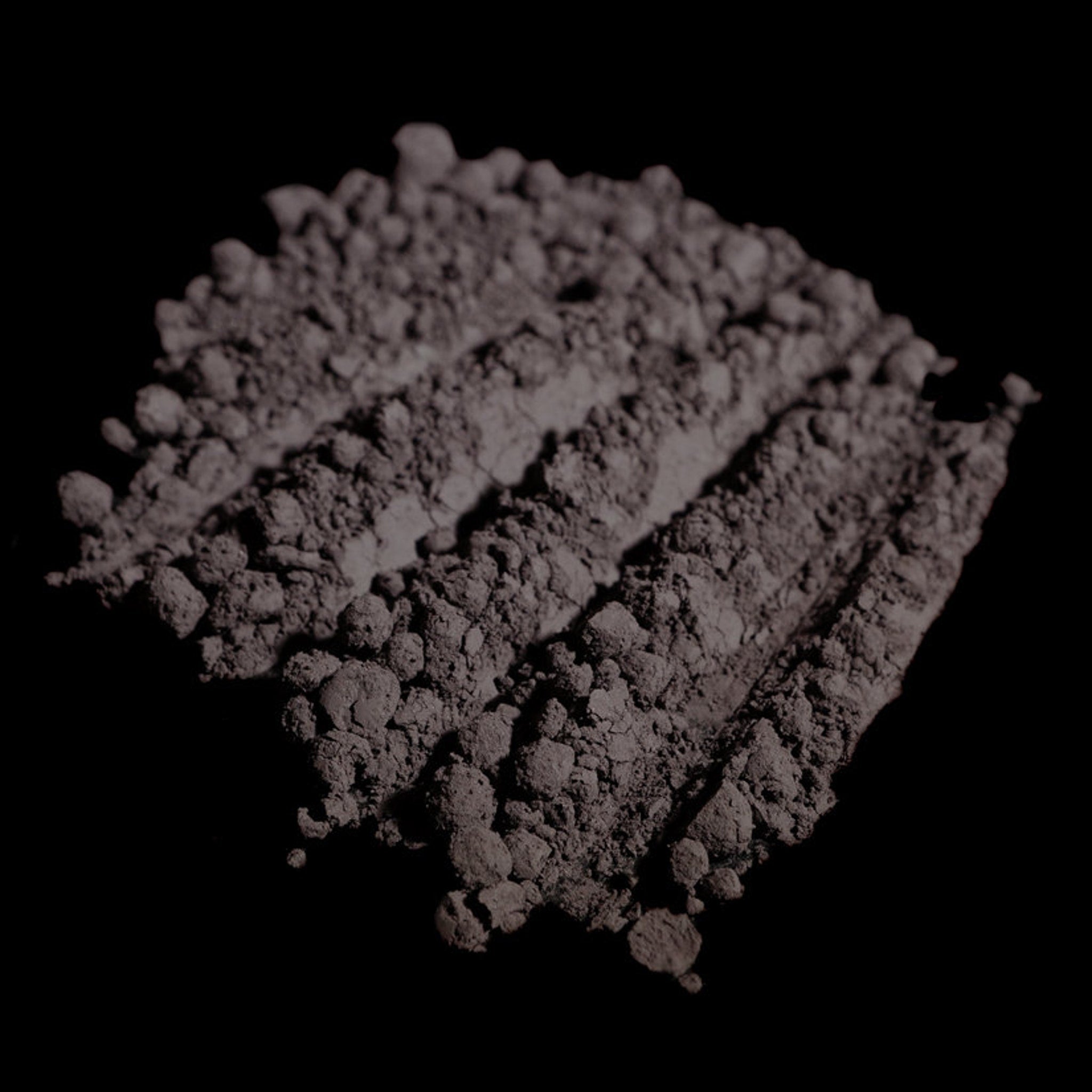Open jar of matte dusty violet loose pigment eyeshadow with dark purple-gray powder visible inside
