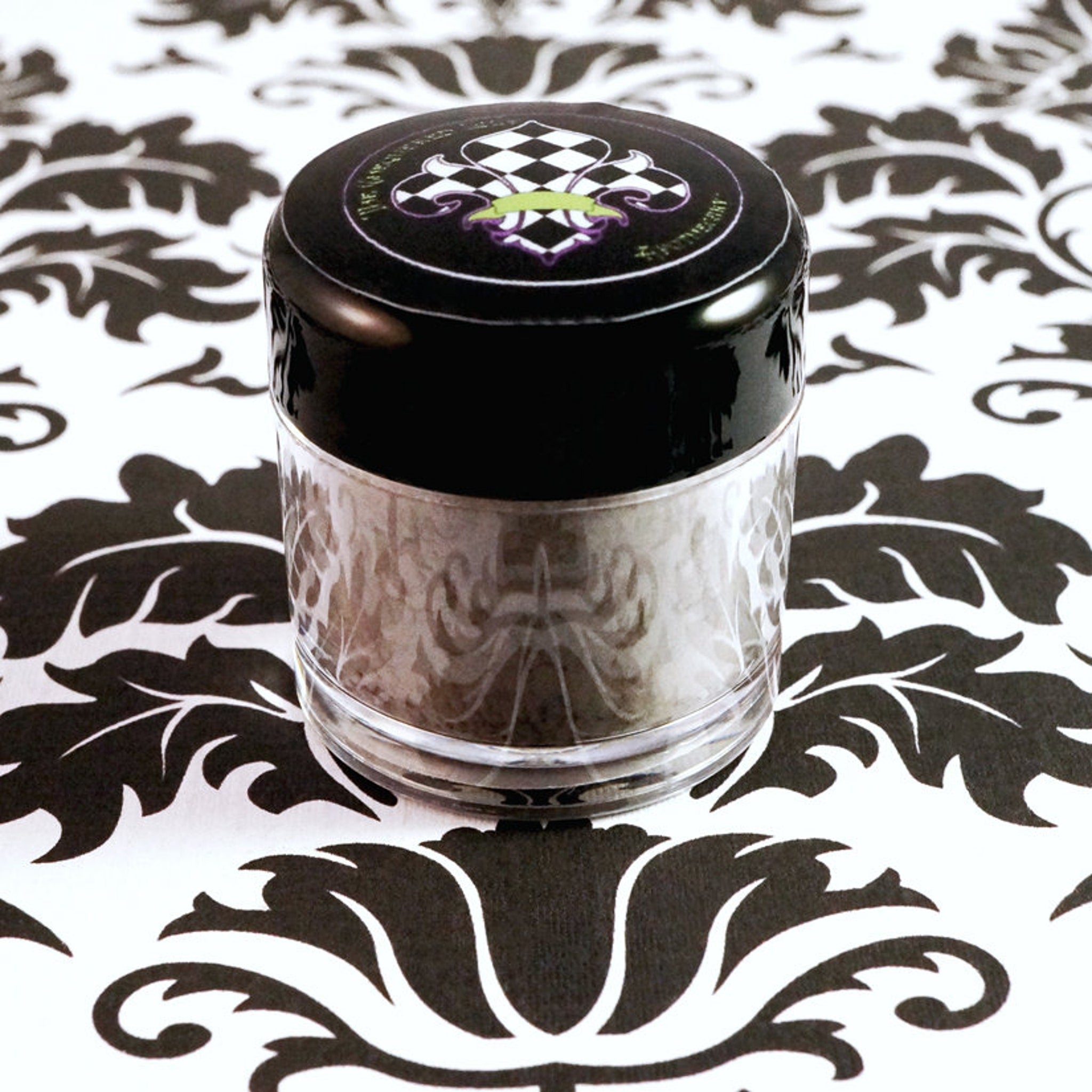 Side view of matte dusty violet loose pigment eyeshadow in dark purple-gray shade with vegan label visible