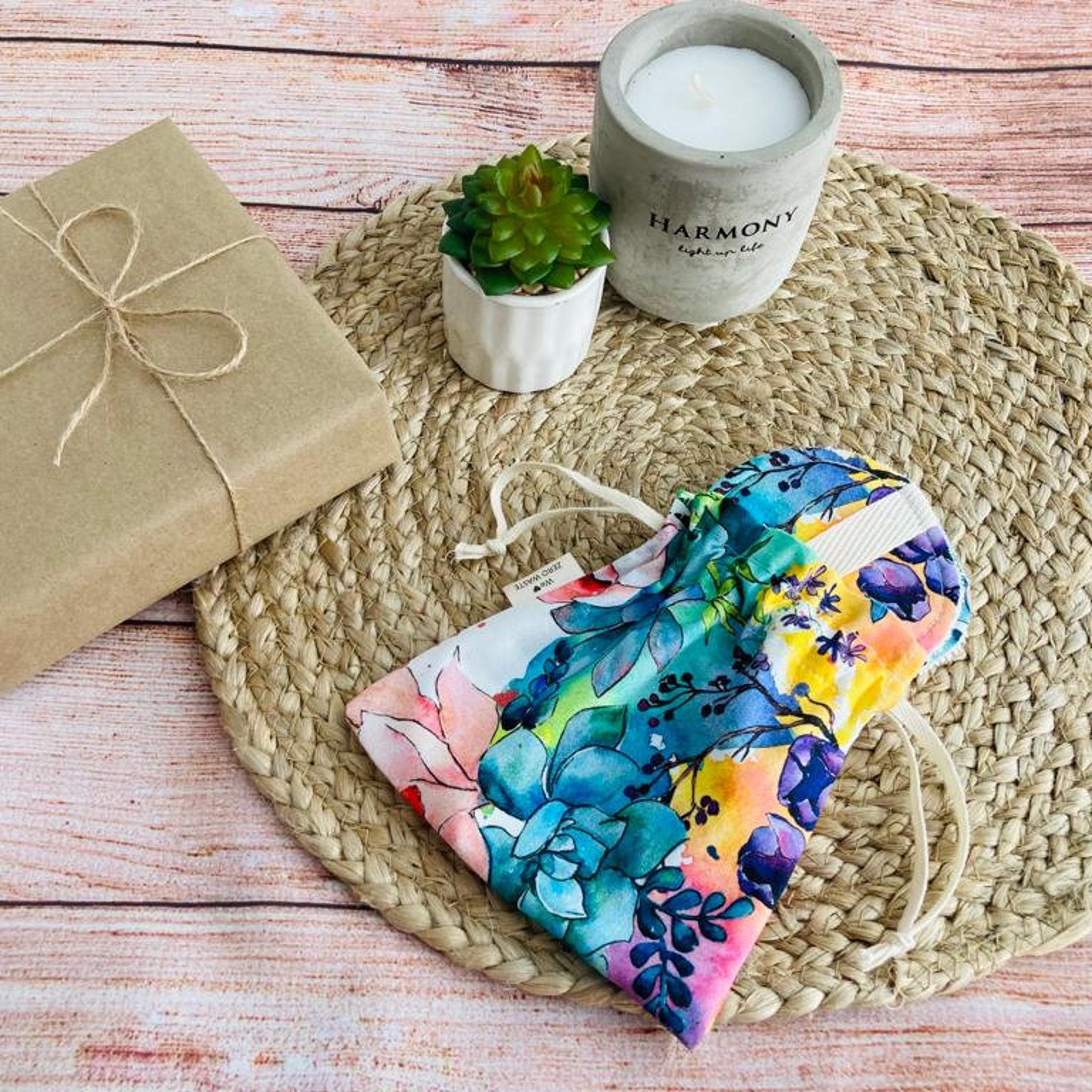 Floral print drawstring bag with blue, yellow, and pink colors, white drawstring, on woven mat