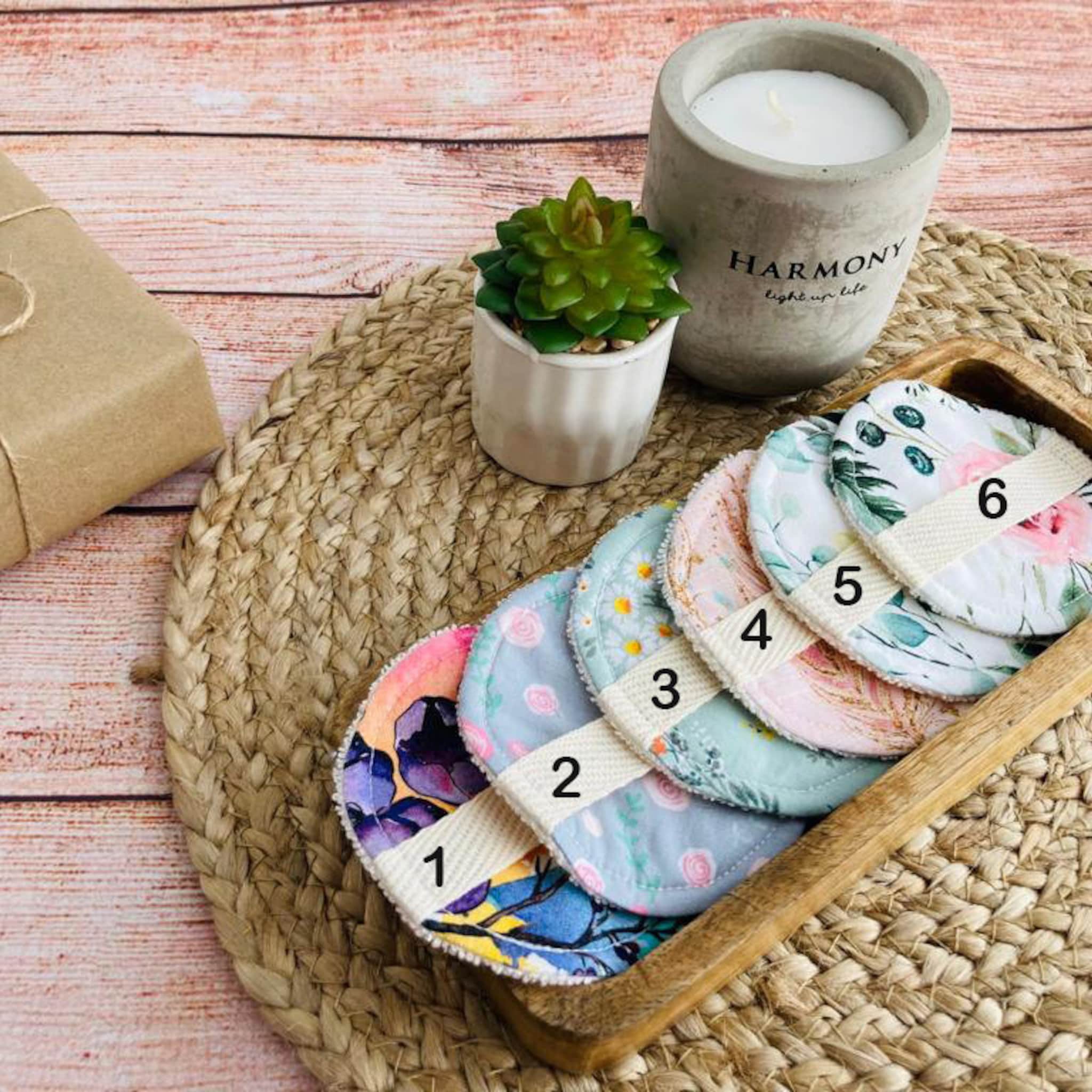 Reusable facial rounds with floral patterns and white straps displayed in wooden tray