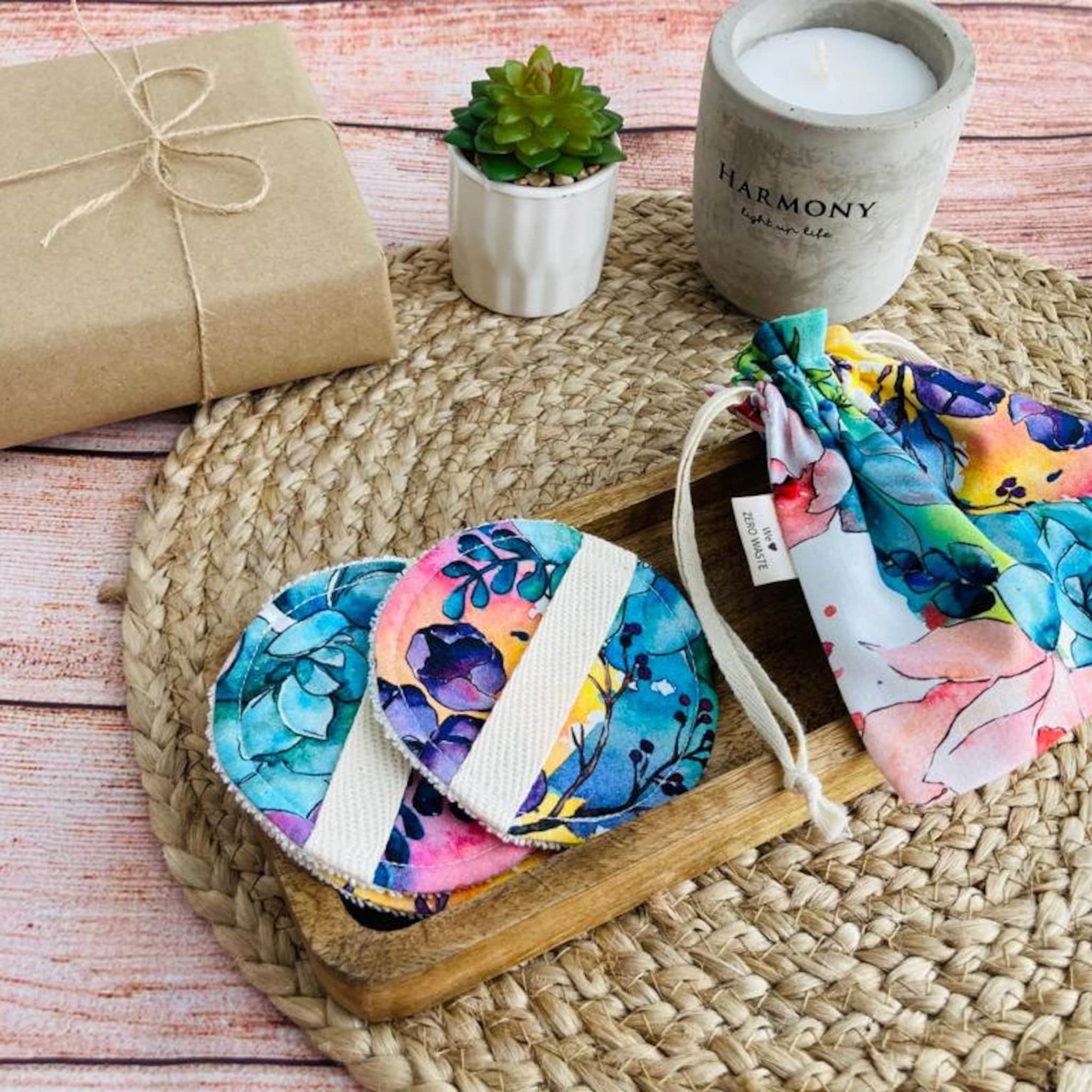 Reusable facial rounds with floral pattern, white trim, and drawstring bag on wooden tray