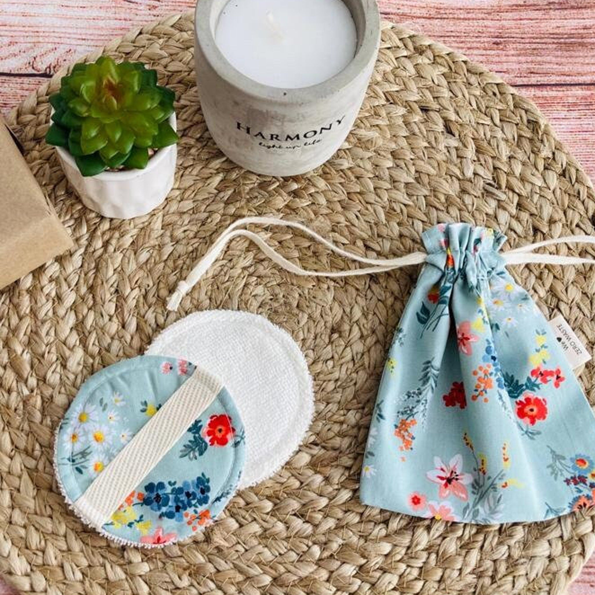 Reusable makeup pads with floral pattern, white fabric, and drawstring bag on woven mat