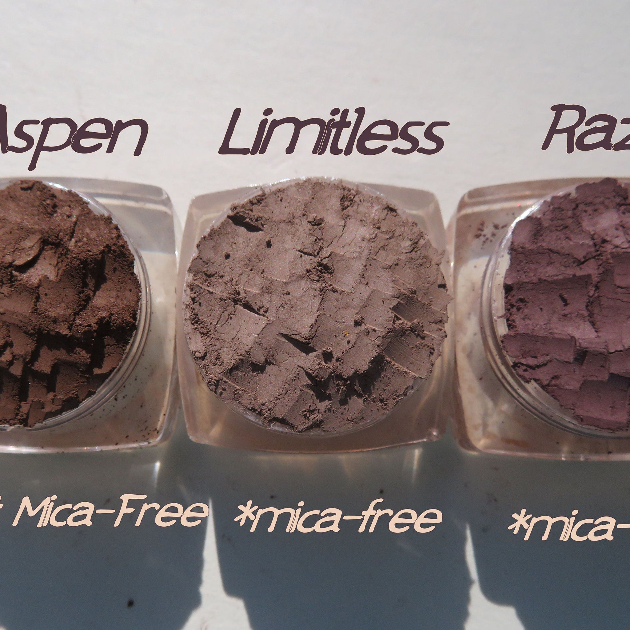 Close-up of matte brown loose pigment eyeshadow set showing fine powder texture in three open jars