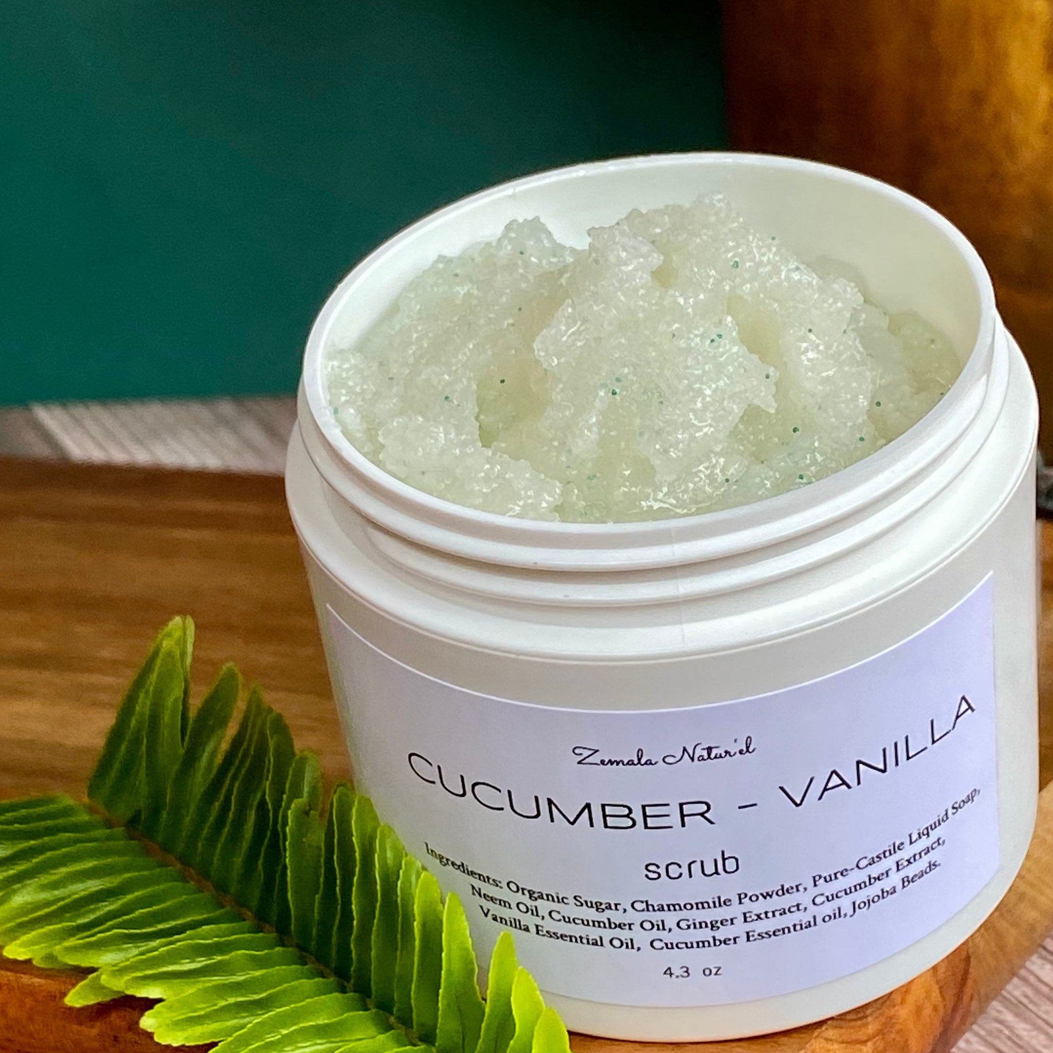 Cucumber vanilla scrub in white jar with green granules, Zemala Naturel label on wood surface