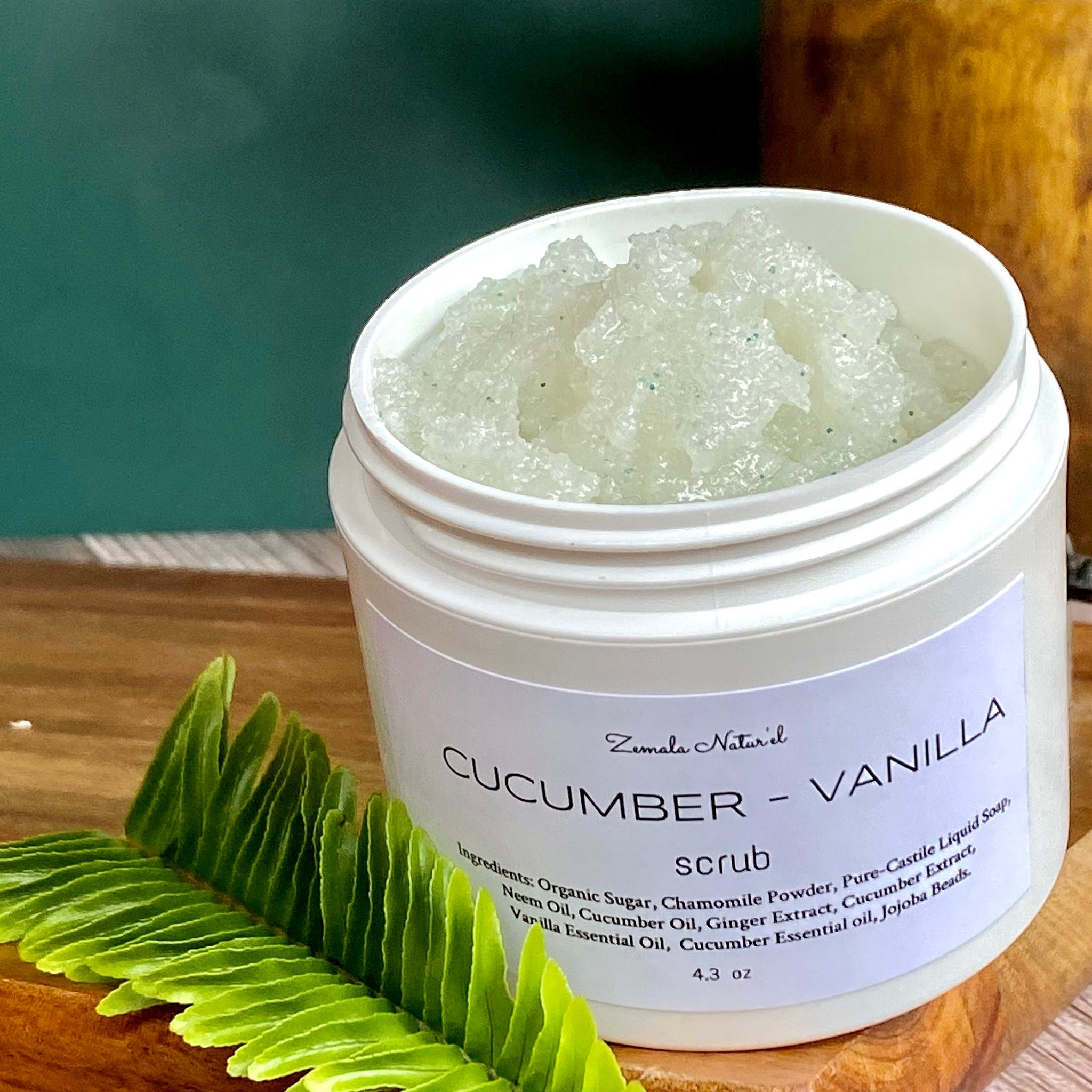 Scrub in white jar with green granules, green leaf, and Zemala Naturel label