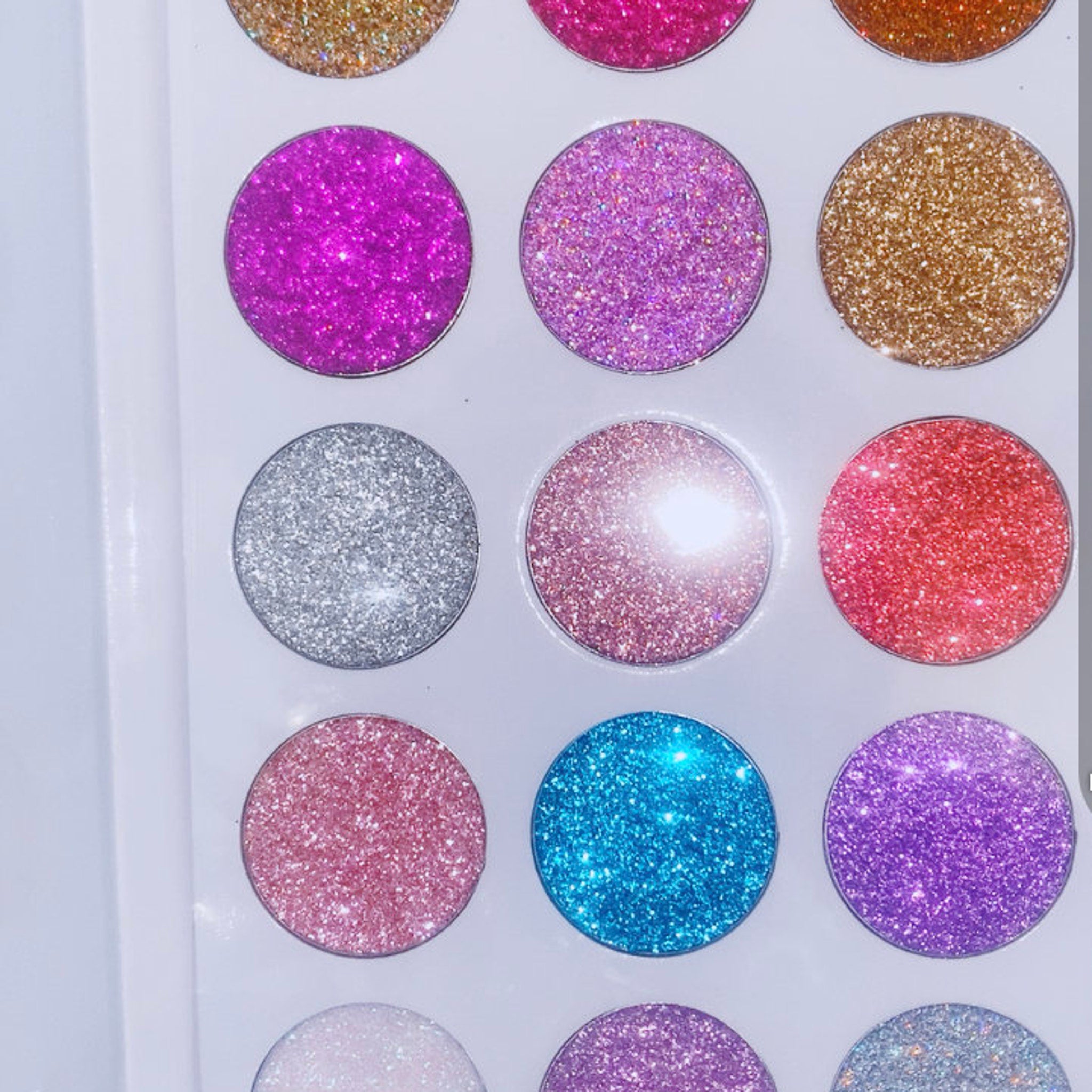 Close-up of shimmering glitter eye shadow palette with vibrant rainbow hues and smooth powder texture