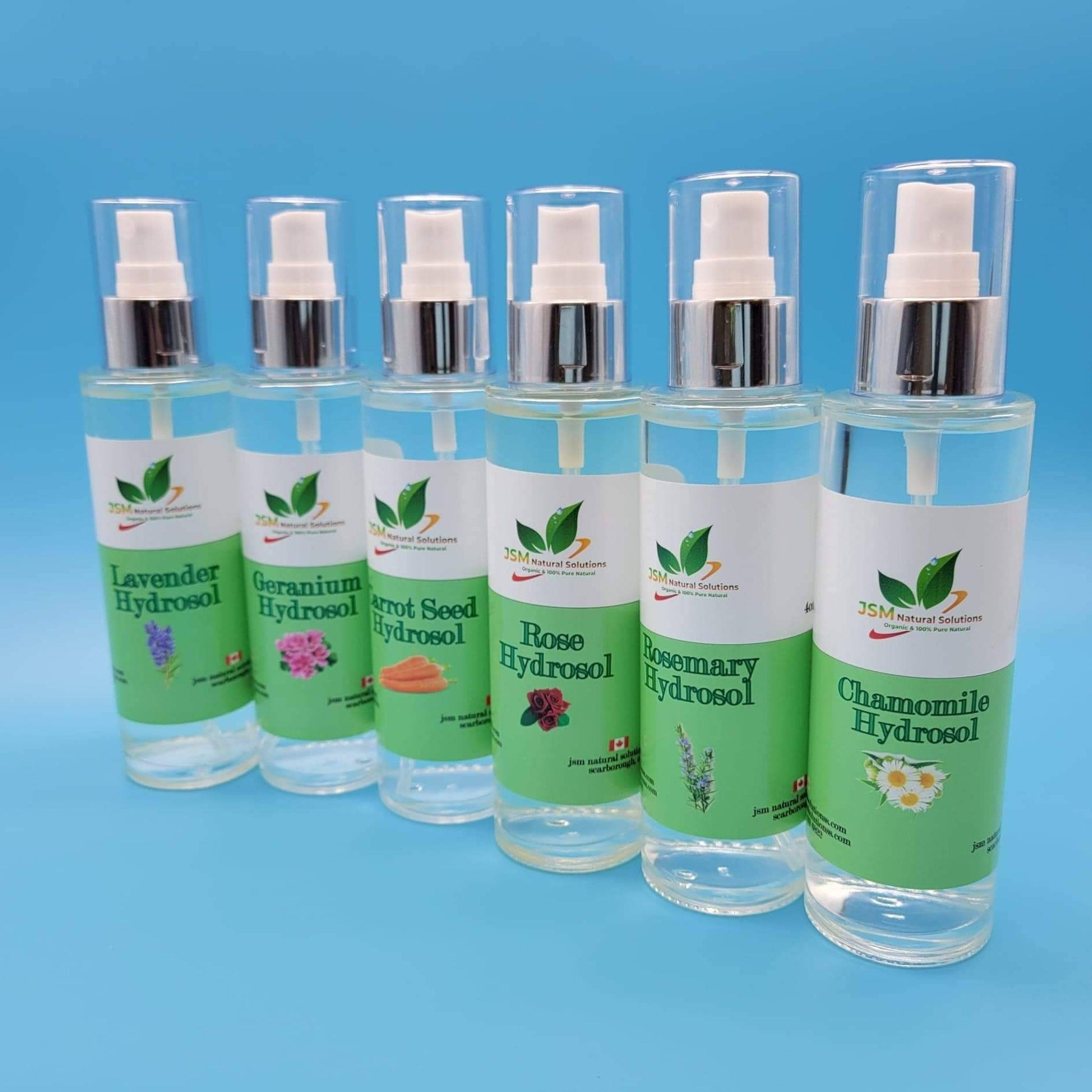 Hydrosol bottles with clear liquid, white and green labels, and silver spray tops on blue background