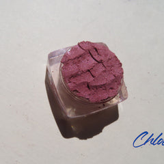 Close-up of CHLOE Vegan Mineral Eyeshadow in dark pink shimmer, loose powder with cruelty-free label, showcasing sparkly texture.