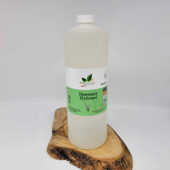Rosemary Hydrosol bottle, clear liquid in a white plastic bottle with white cap, on a wood slab