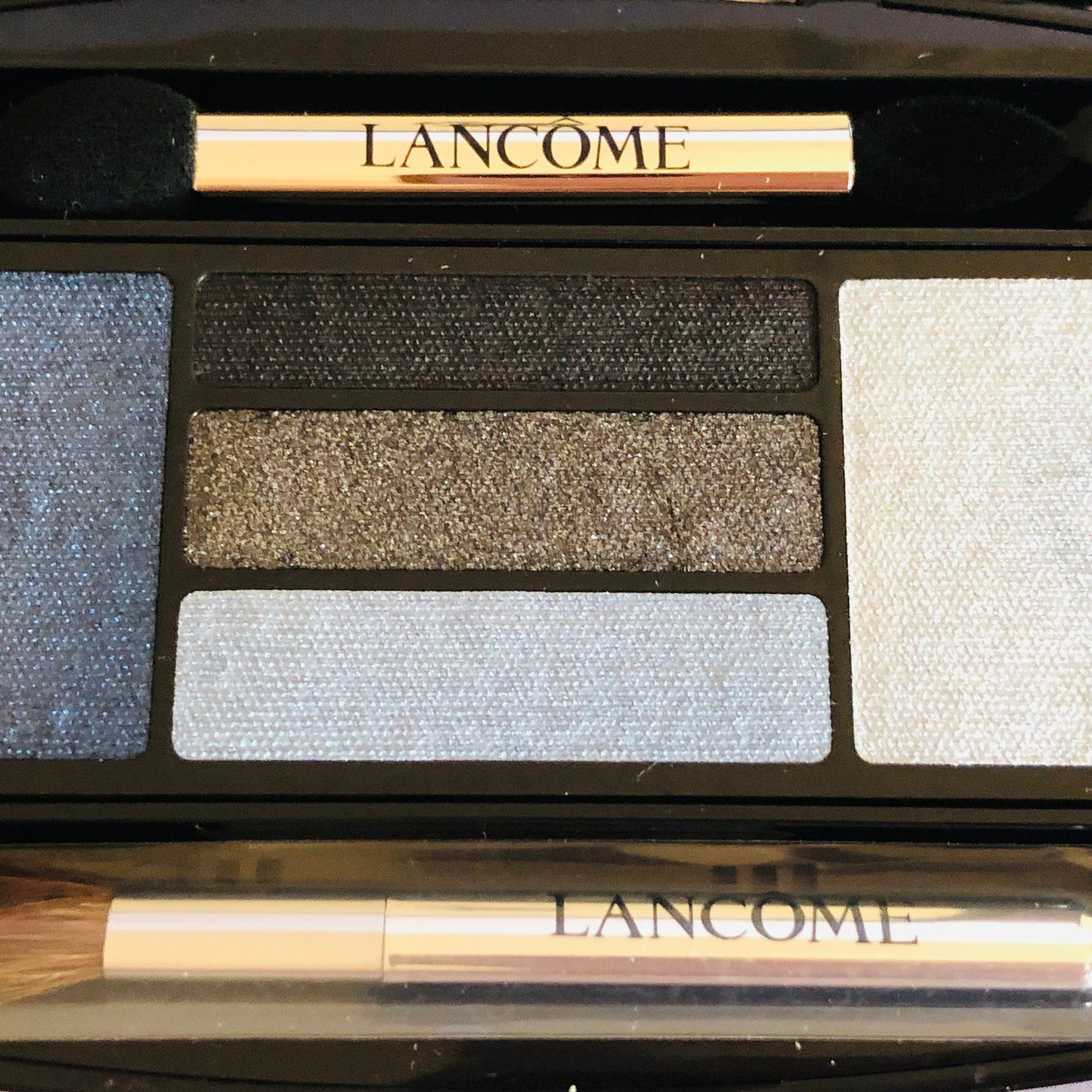 Close-up of LANCÔME x Alber Elbaz taupe eyeshadow palette showing shimmering metallic textures and sleek black packaging