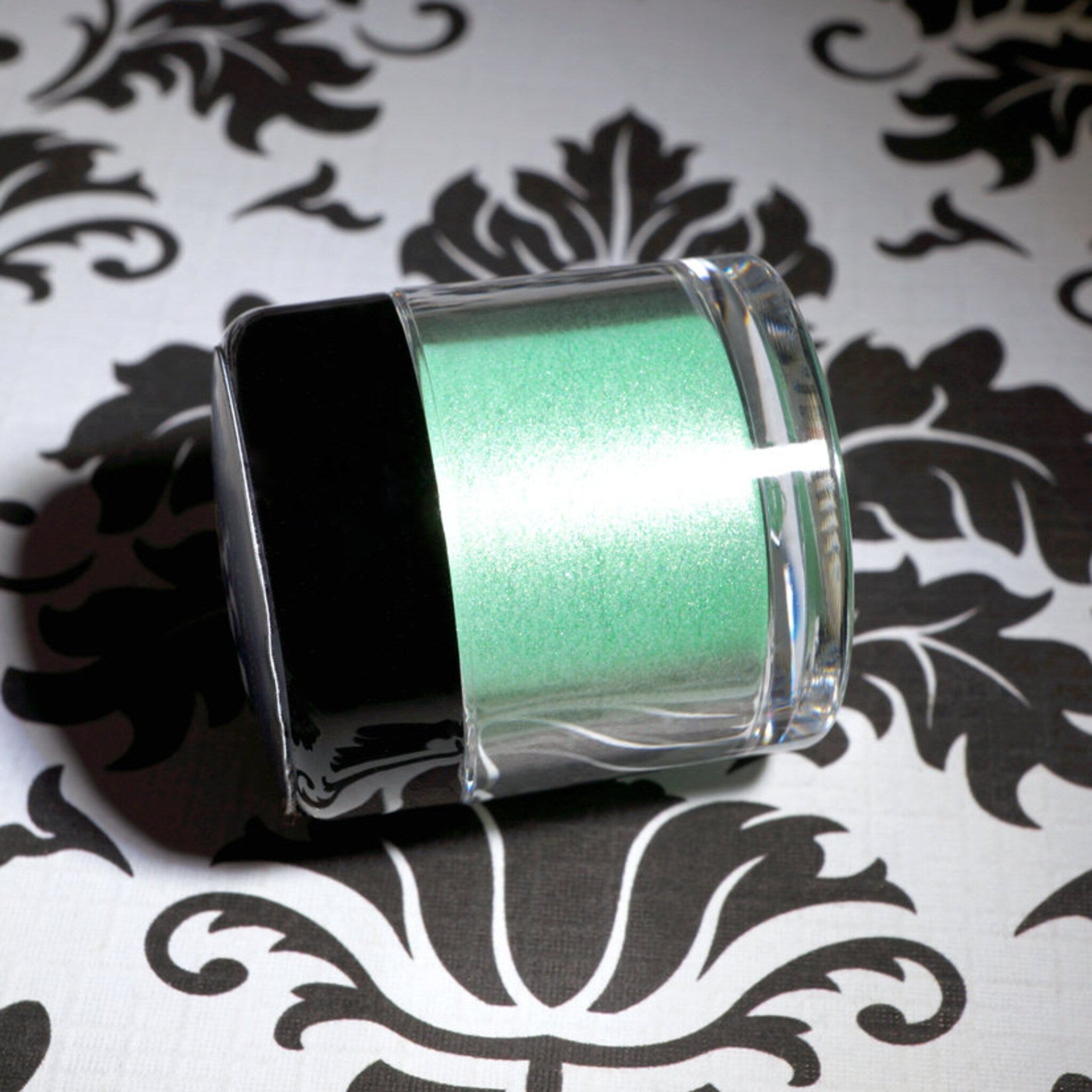 Close-up of loose iridescent lime green eyeshadow pigment shimmering with metallic candy apple highlights